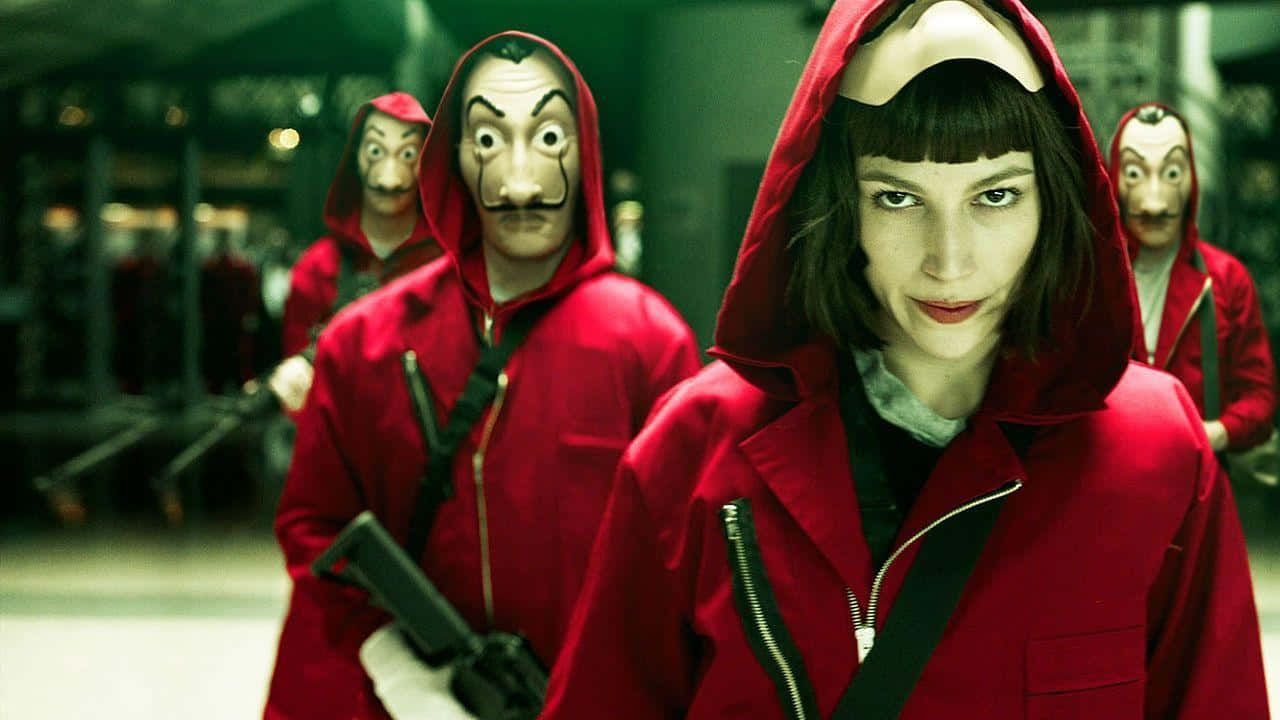 Money Heist 桌布 壁紙 — 一名身穿紅色連帽外套的女子直視前方，而戴著面具、穿著相同紅色服裝的人物站在她身後，在燈光昏暗的車站裡。