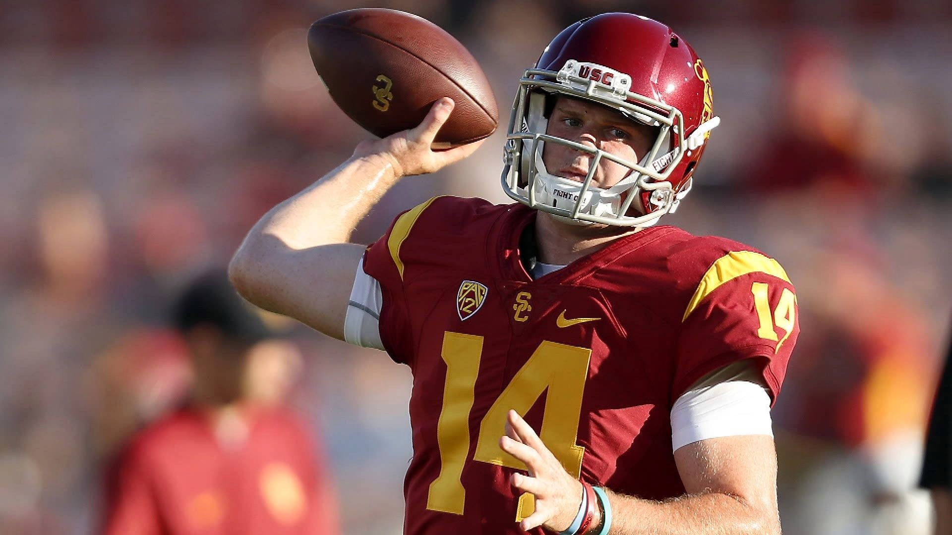 Usc Football 桌布 壁紙 — 一名身穿紅金色制服嘅USC足球四分衛喺陽光普照嘅比賽中準備投球。