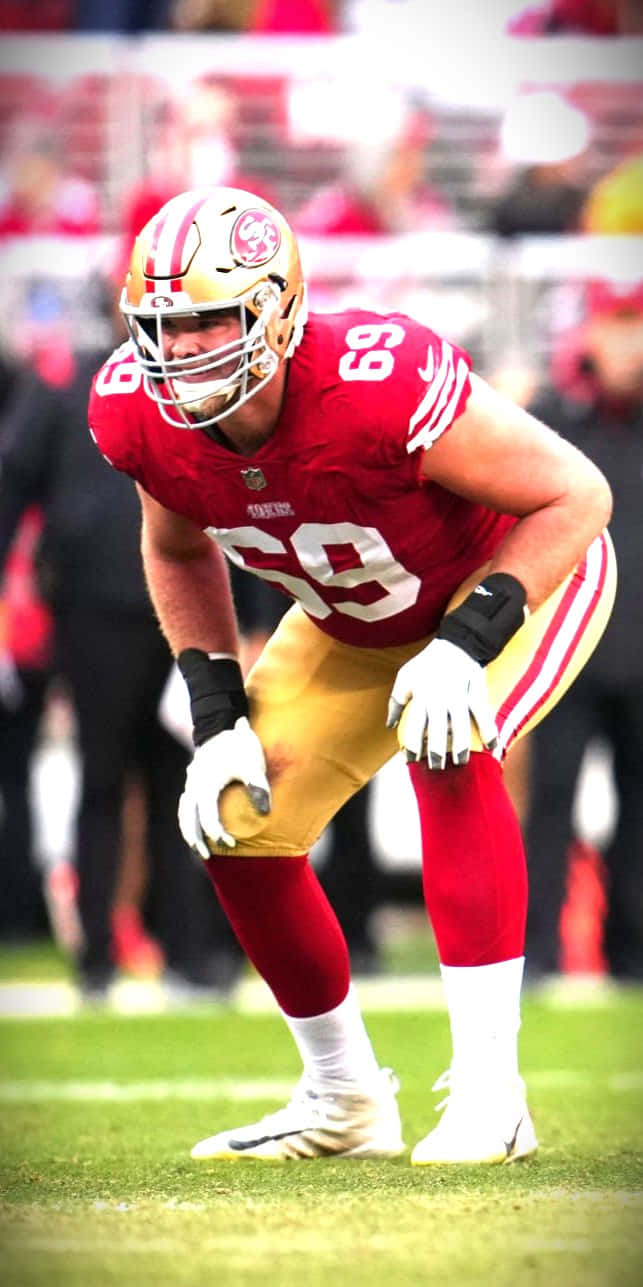 Mike Mcglinchey 桌布 壁紙 — 一名身穿紅金色球衣的三藩市四九人美式足球員在綠色球場上激烈蹲伏。