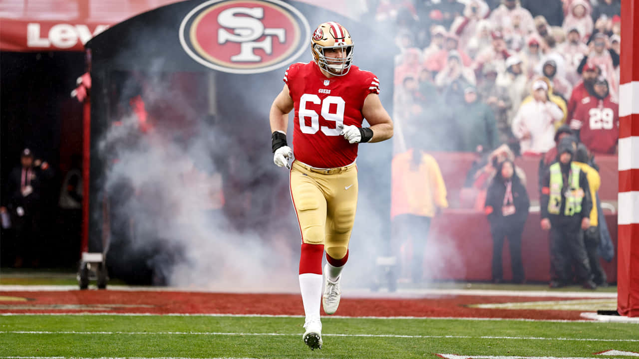 Mike Mcglinchey 桌布 壁紙 — 一名身穿紅金色球衣的三藩市四九人美式足球員在李維斯球場穿過煙霧跑入球場。