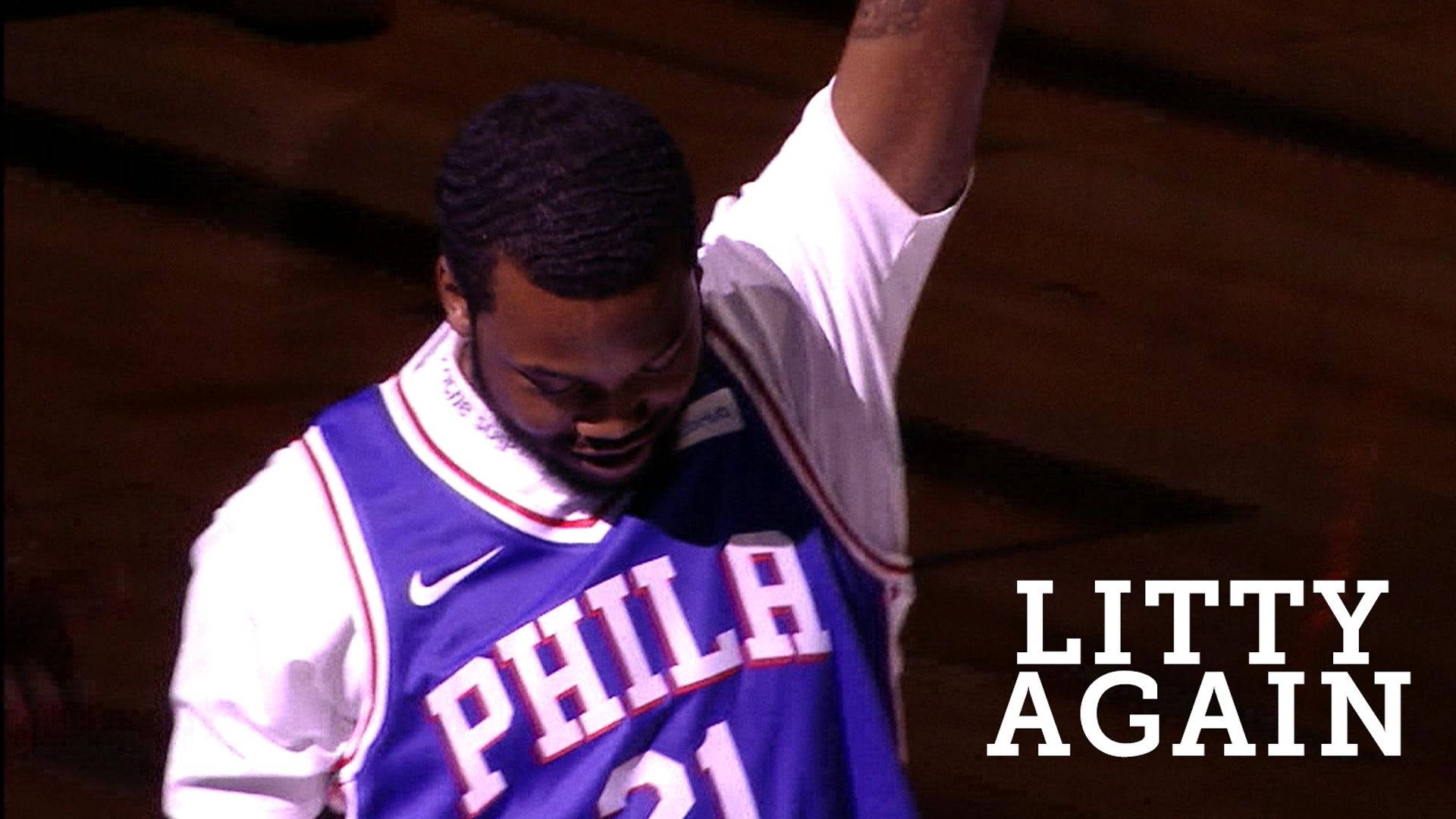 Meek Mill《Litty Again》 壁紙 — 一名身穿紫白色費城球衣的籃球運動員在明亮的場館燈光下，於木地板上高舉手臂慶祝勝利。