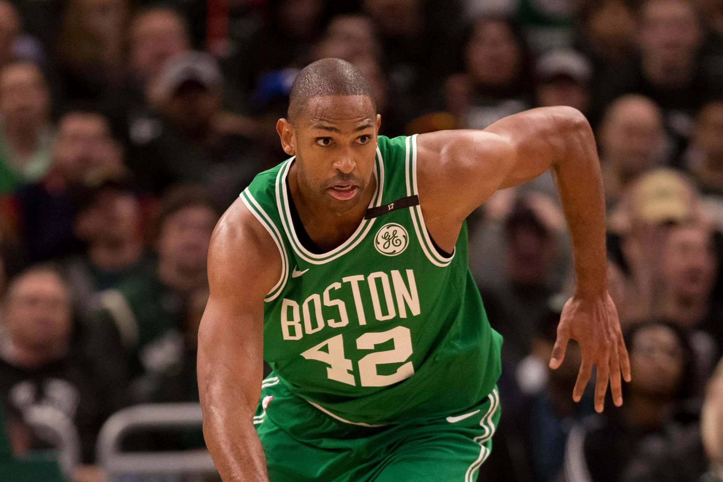 Al Horford 桌布 壁紙 — 一名身穿綠色球衣、號碼42的波士頓塞爾特人籃球運動員在比賽中激烈運球，背景是模糊的人群。