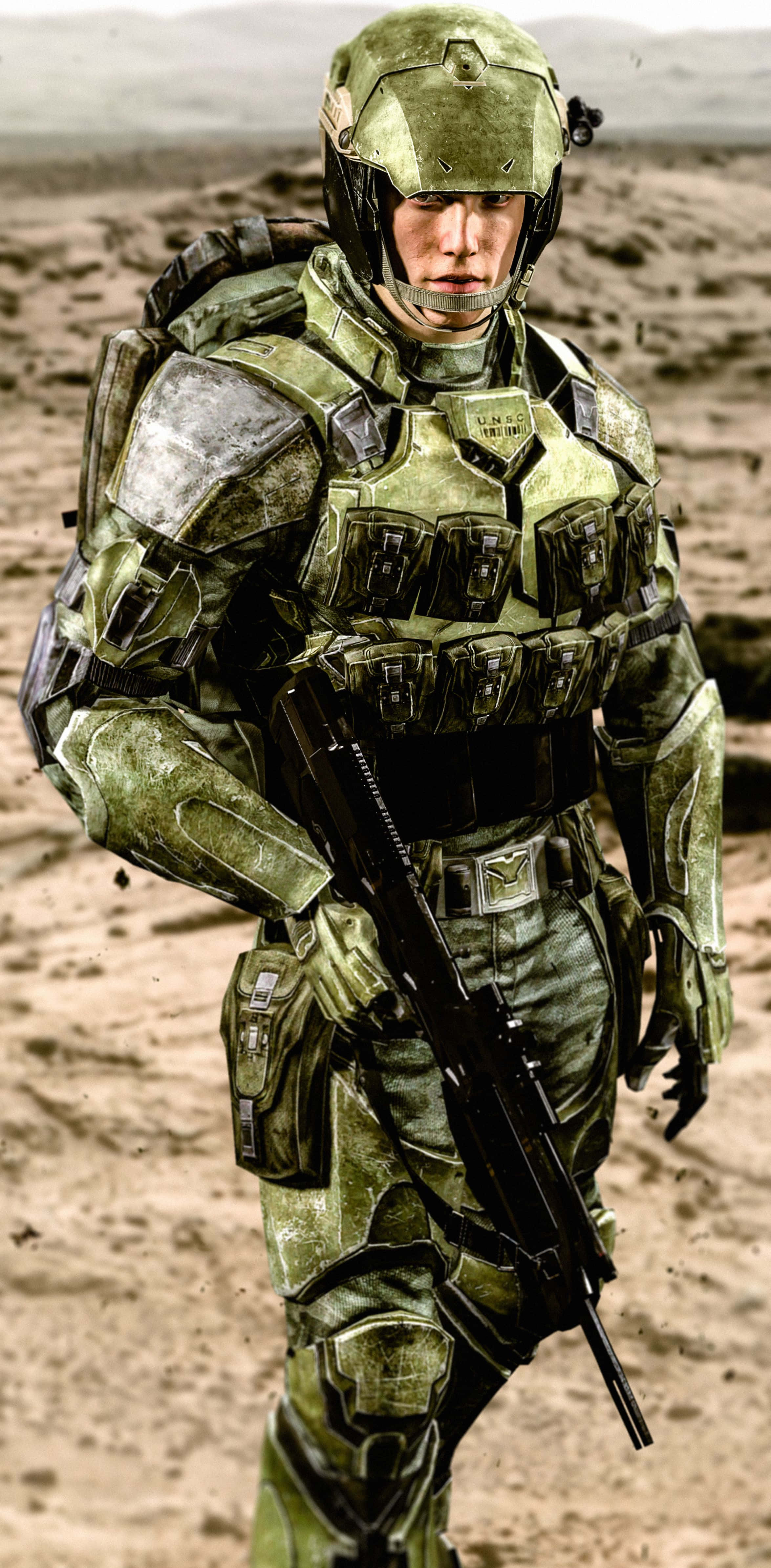 Halo Unsc 桌布 壁紙 — 一名身穿綠色裝甲戰鬥裝備的士兵在荒蕪的沙漠景觀中持步槍保持警覺。
