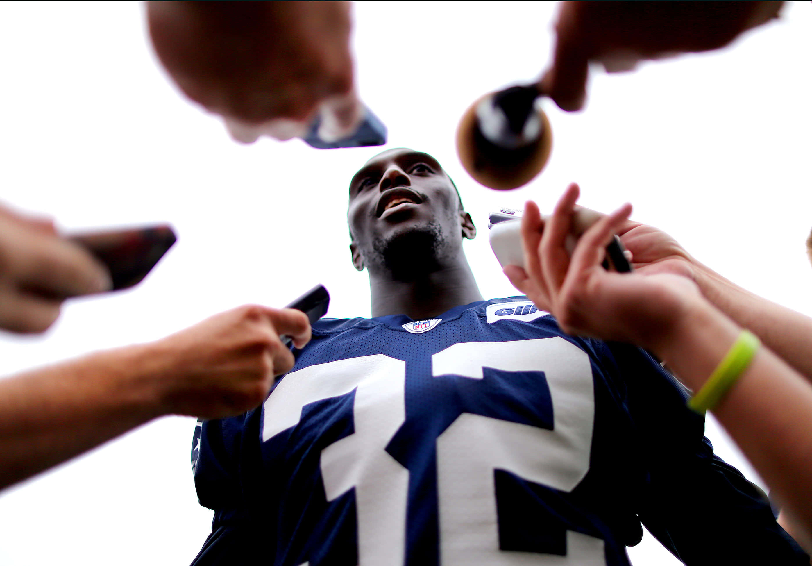 Devin Mccourty 桌布 壁紙 — 一名身穿藍色球衣、號碼72的美式足球員被手持咪高峰和電話的記者包圍。