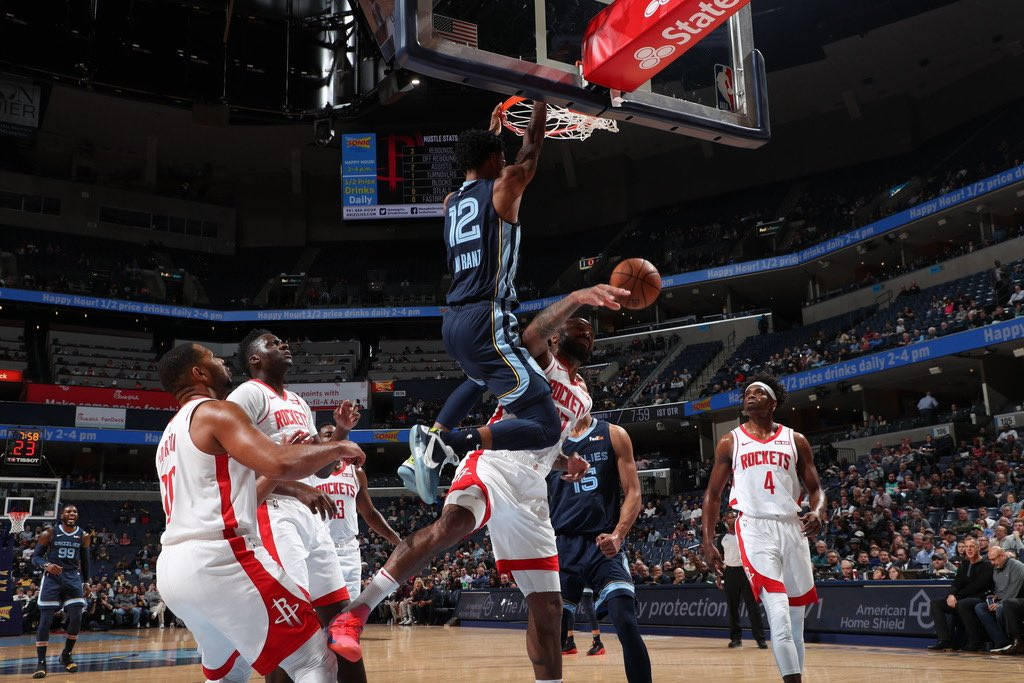 NBA 桌布 壁紙 — 一名身穿藍色球衣的籃球運動員在擠滿觀眾的場館中，被防守球員包圍下灌籃。