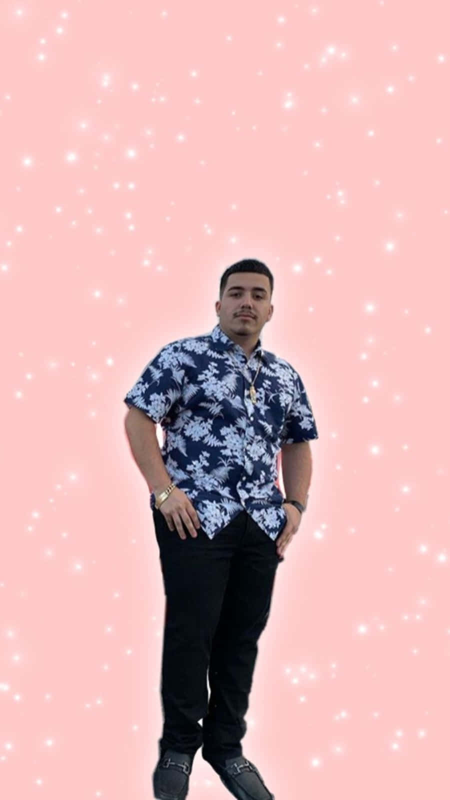 Eslabon Armado 桌布 壁紙 — 一名身穿藍色花卉圖案襯衫的男子，自信地站在閃爍的粉紅色背景前。