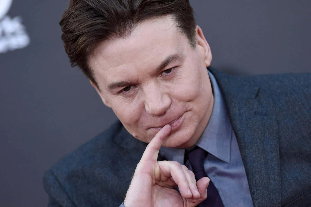 Mike Myers 桌布 壁紙 — 一名身穿藍色西裝的男子在深色背景下將手指放在唇邊低聲說出秘密。