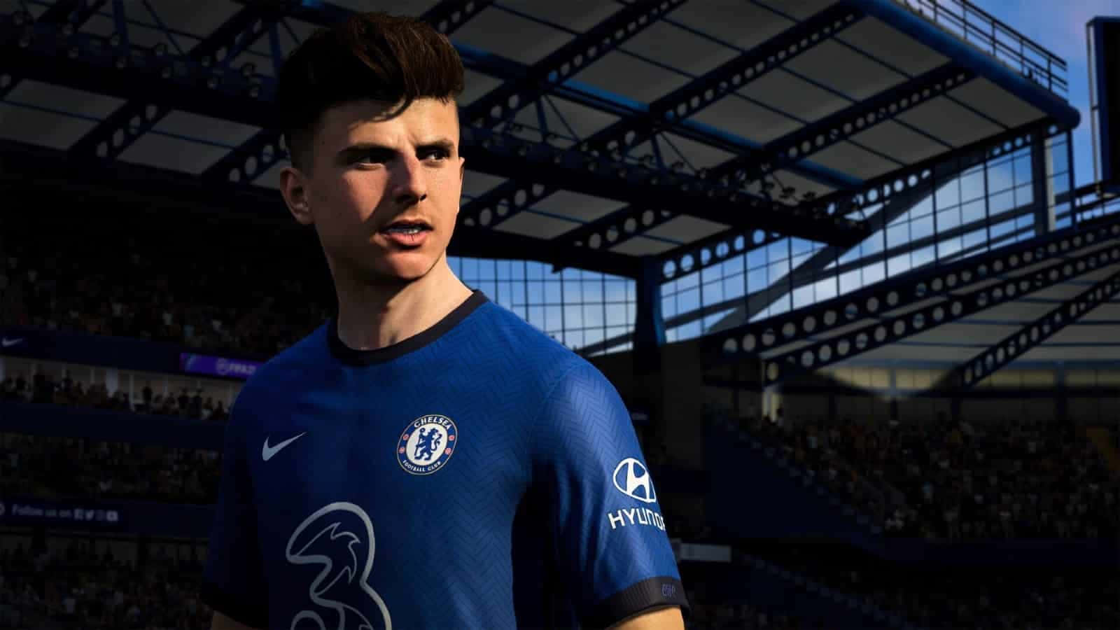 Fifa 22 桌布 壁紙 — 一名身穿藍色車路士球衣的足球員站在球場上，球迷和明亮的陽光在看台上投下陰影。