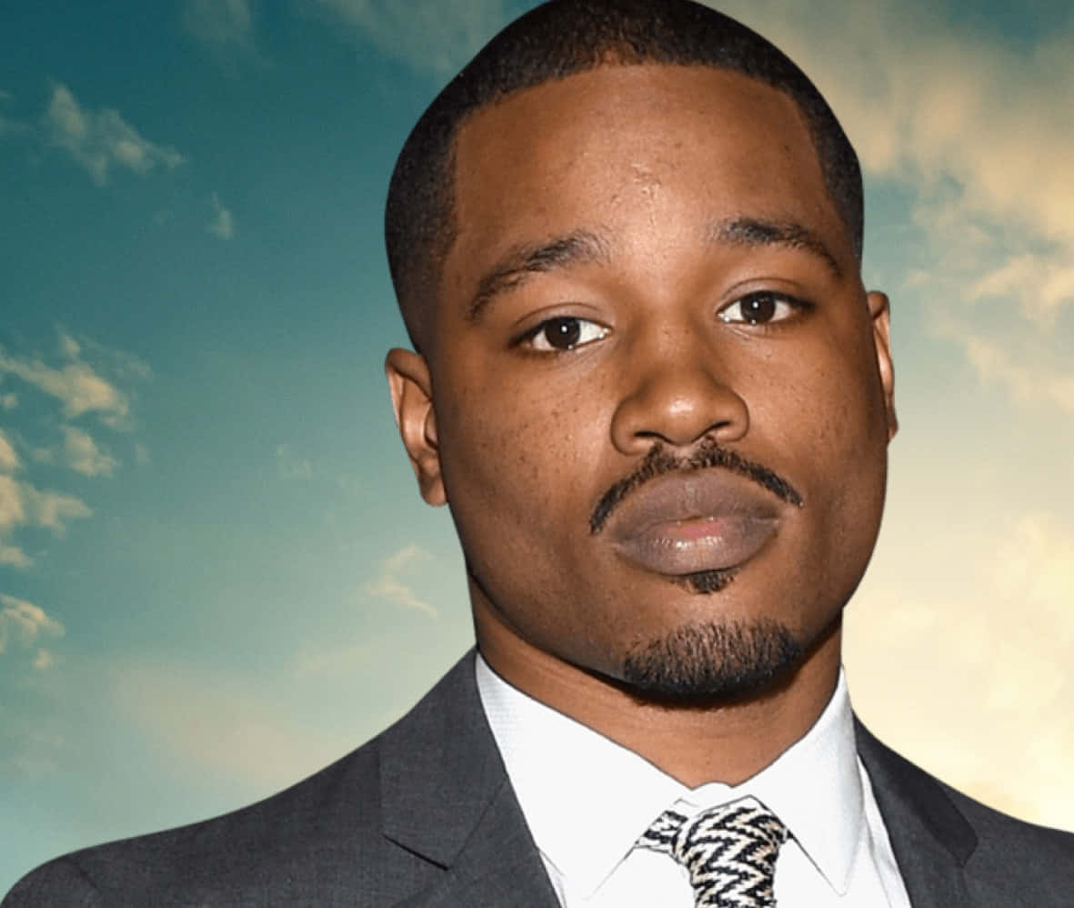 Ryan Coogler 桌布 壁紙 — 一名身穿西裝及圖案領帶的男子，在藍天白雲的柔和背景下直視鏡頭。