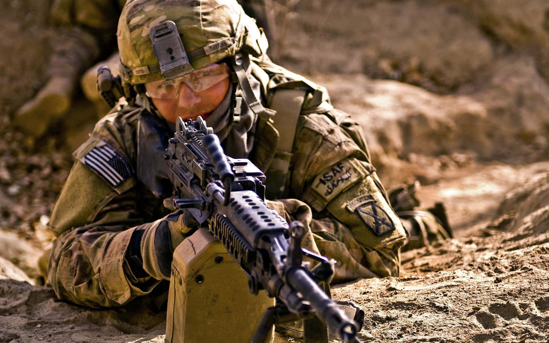 Army 桌布 壁紙 — 一名身穿迷彩裝備的士兵在岩石沙漠地形中蹲下，專注地瞄準步槍。
