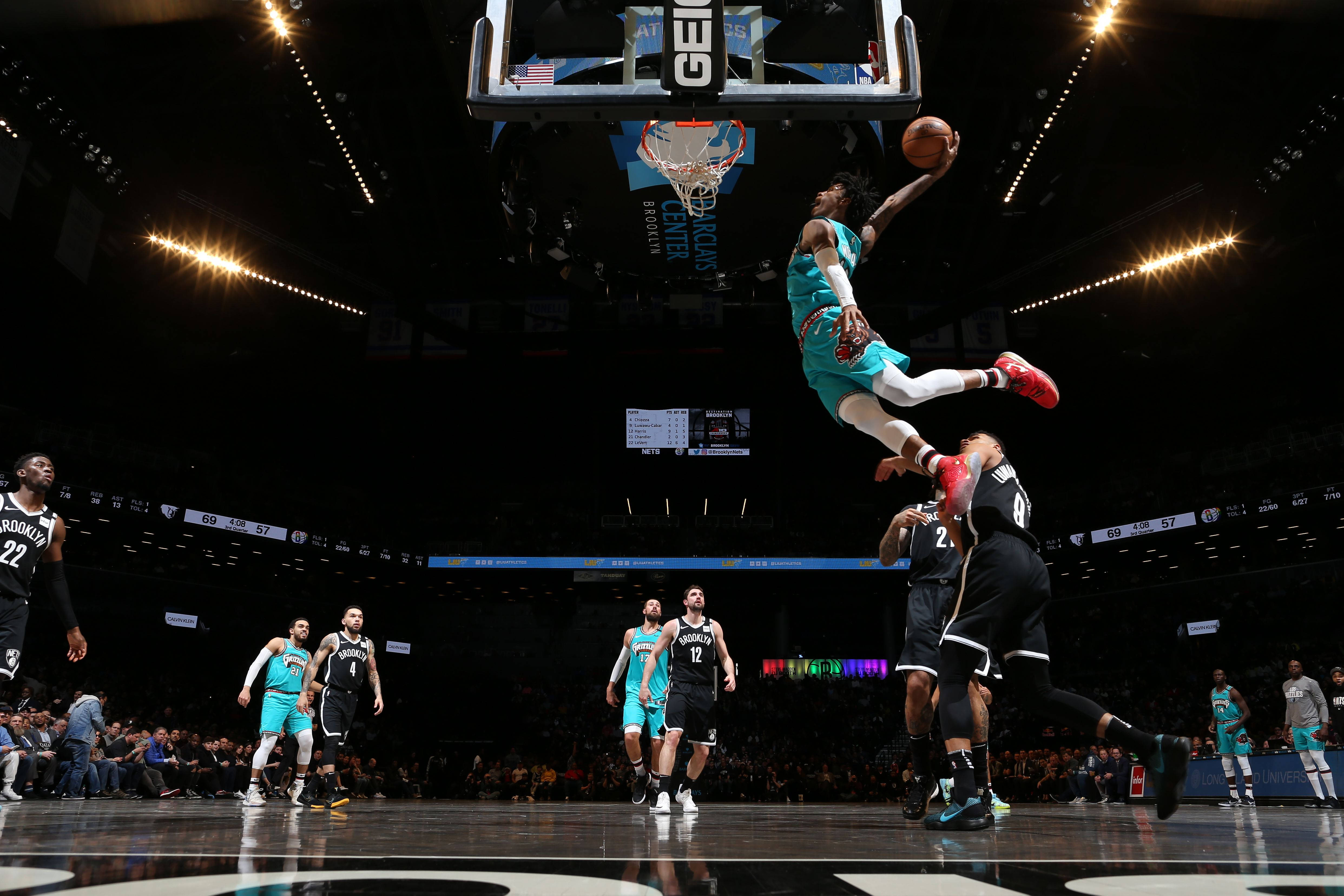Brooklyn Nets 桌布 壁紙 — 一名身穿青綠色的籃球運動員高高躍起準備灌籃，防守球員在場館燈光下跳起封阻。