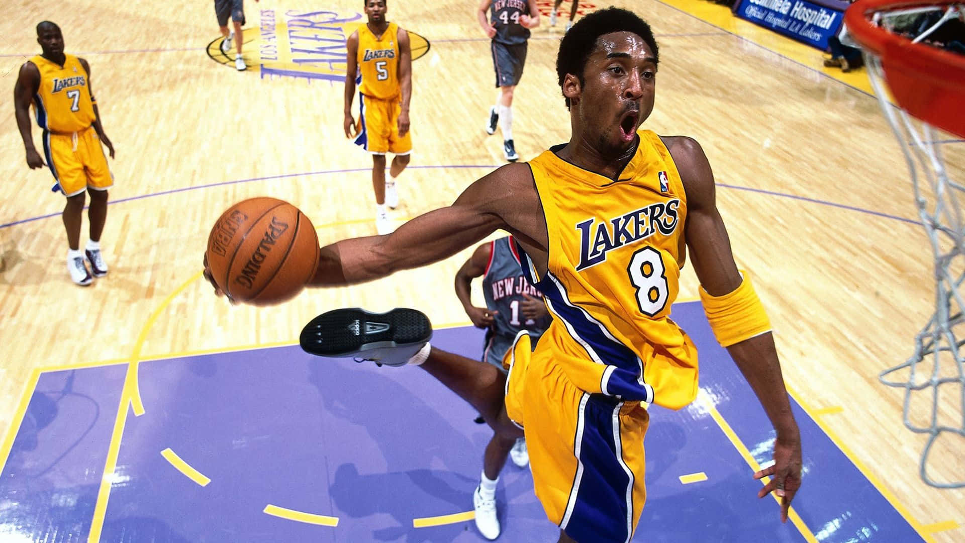 Kobe 桌布 壁紙 — 一名身穿黃色湖人隊球衣的籃球運動員在比賽中充滿活力地跳向籃框，專注力極強。