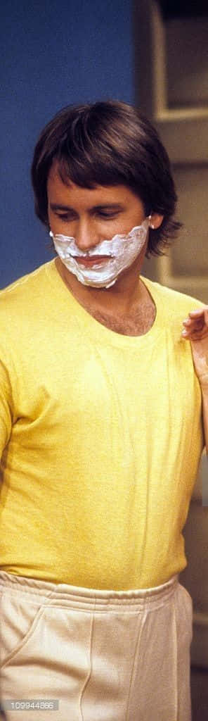 John Ritter 桌布 壁紙 — 一名身穿黃色襯衫的男子在攝影棚環境中，專注地將剃鬚膏塗在臉上。