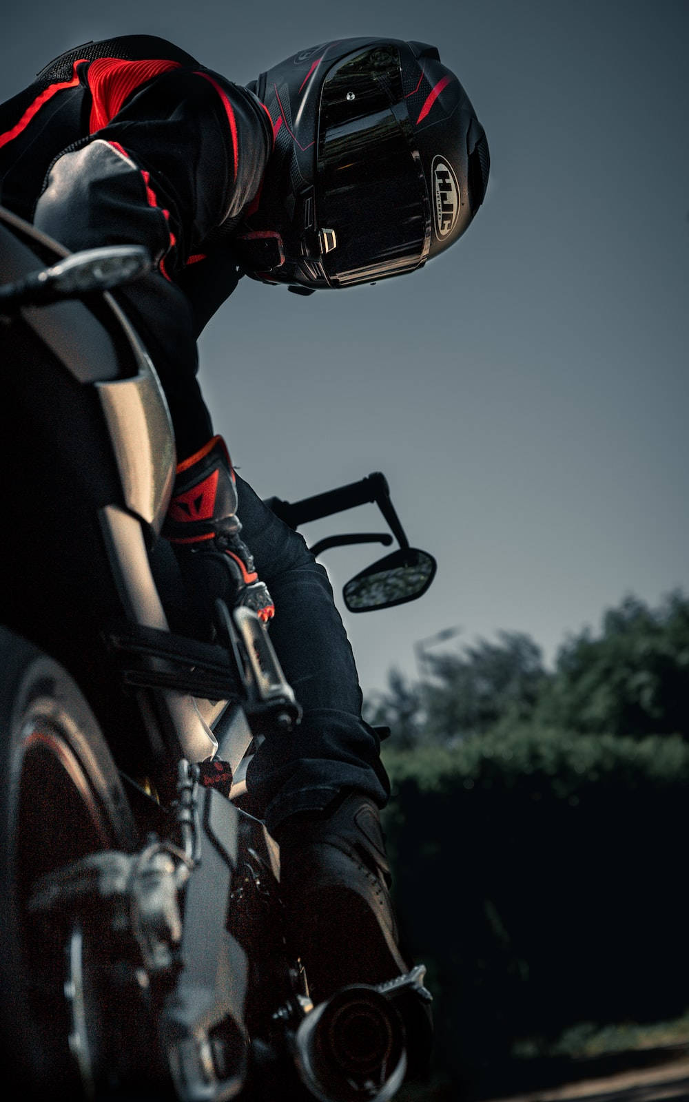 Bike Rider 桌布 壁紙 — 一名身穿黑紅色裝備的電單車手，在昏暗的天空下，騎著流線型電單車傾斜入彎。