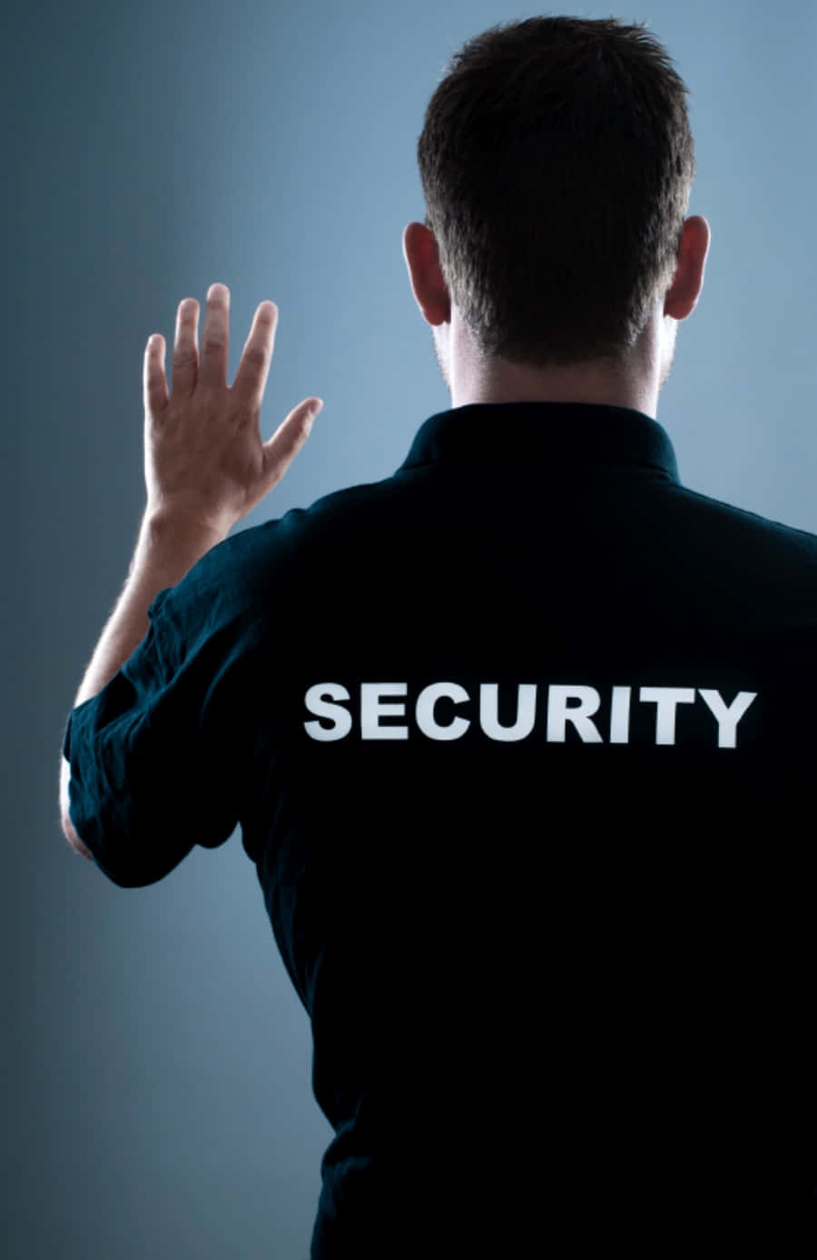 security 桌布 壁紙 — 一名身穿黑色制服、背後印有'SECURITY'的保安人員，在清涼的藍色漸變背景前舉起手做出停止手勢。