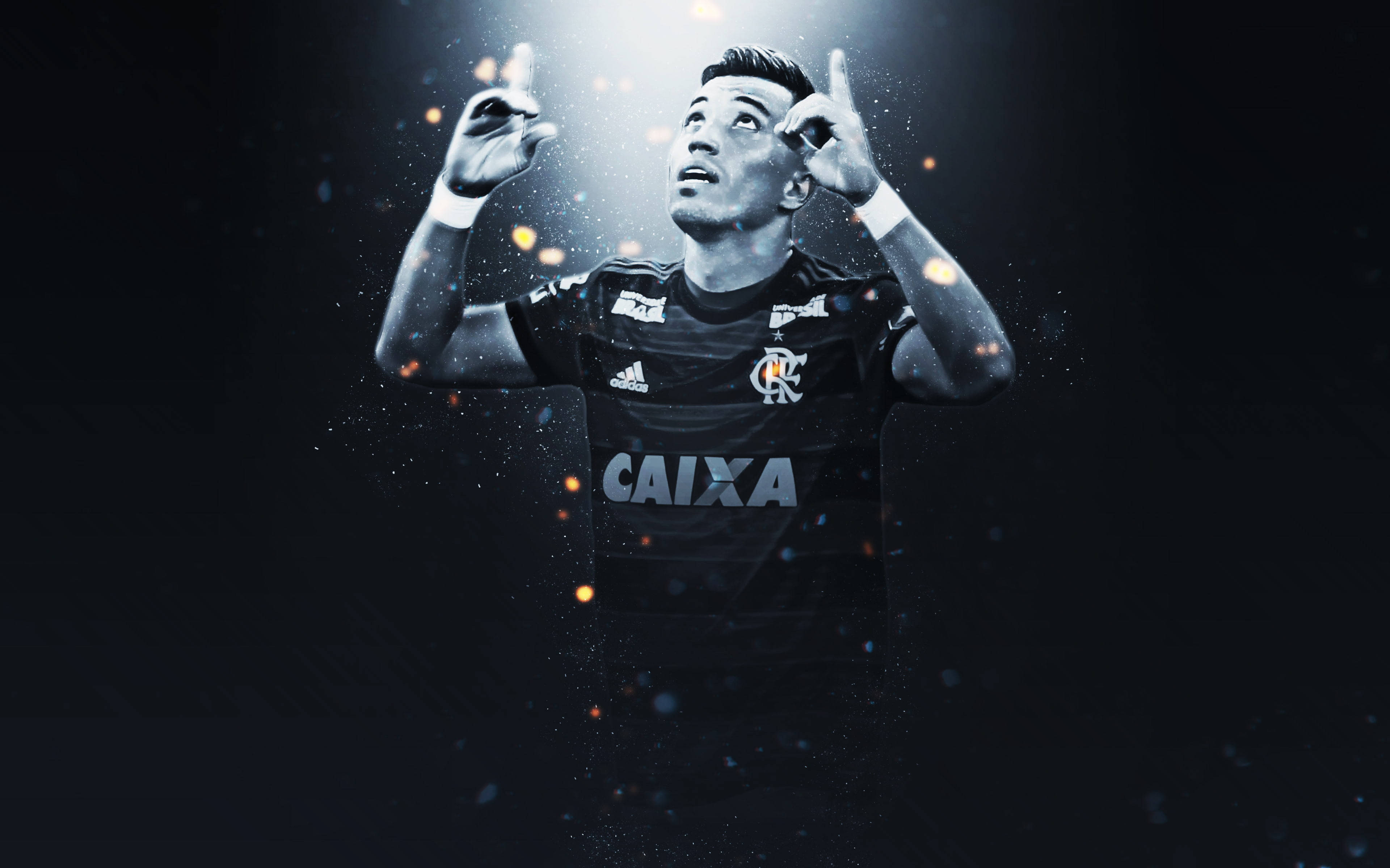 Flamengo FC Fernando Uribe 壁紙 — 一名身穿黑色球衣的足球員在戲劇性的聚光燈下做出『OK』手勢，發光粒子在他周圍旋轉。