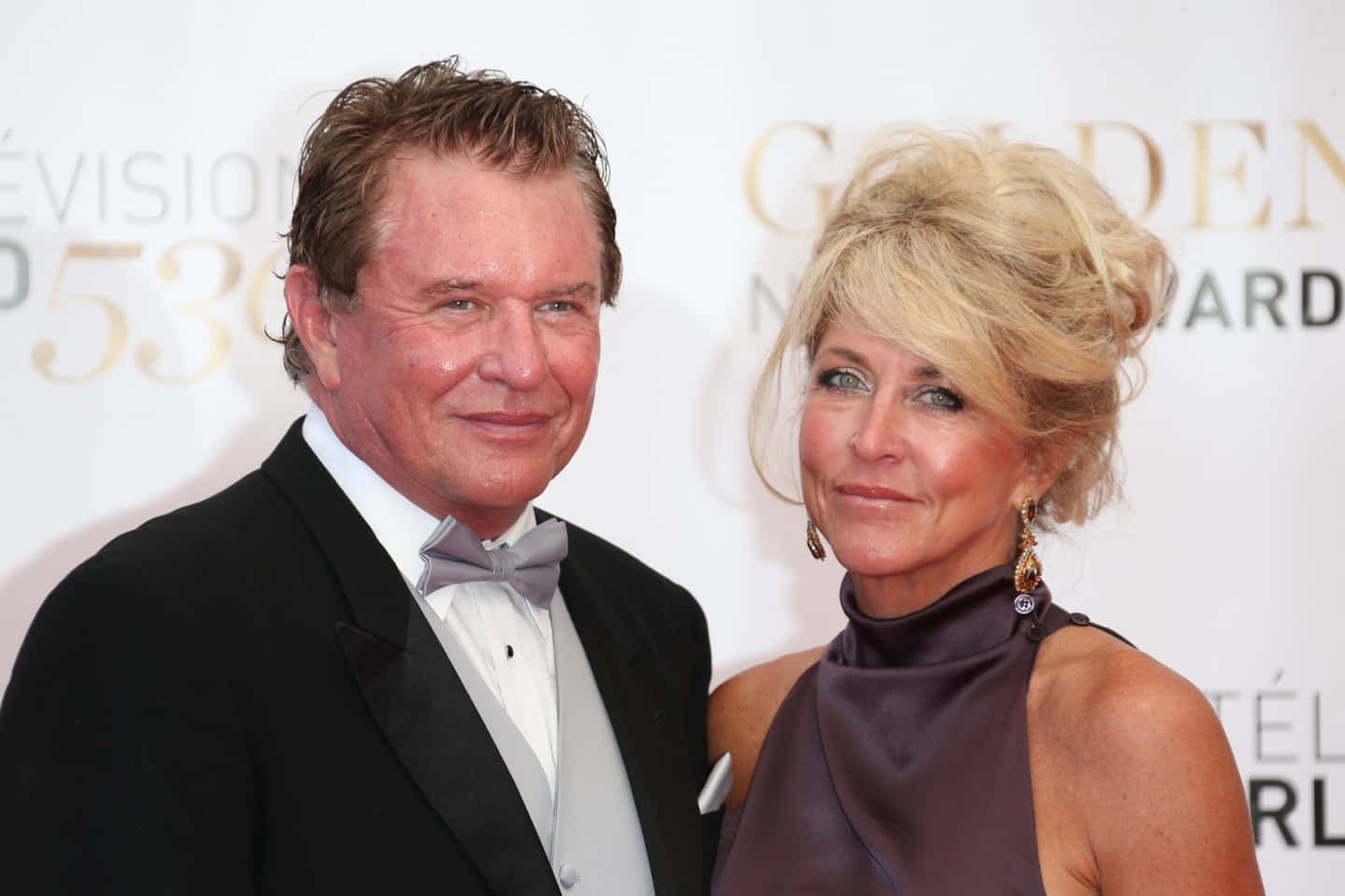 Tom Berenger 桌布 壁紙 — 一名身穿黑色禮服的男士和一名身穿紫色連衣裙的女士在金球獎紅地毯上合影。
