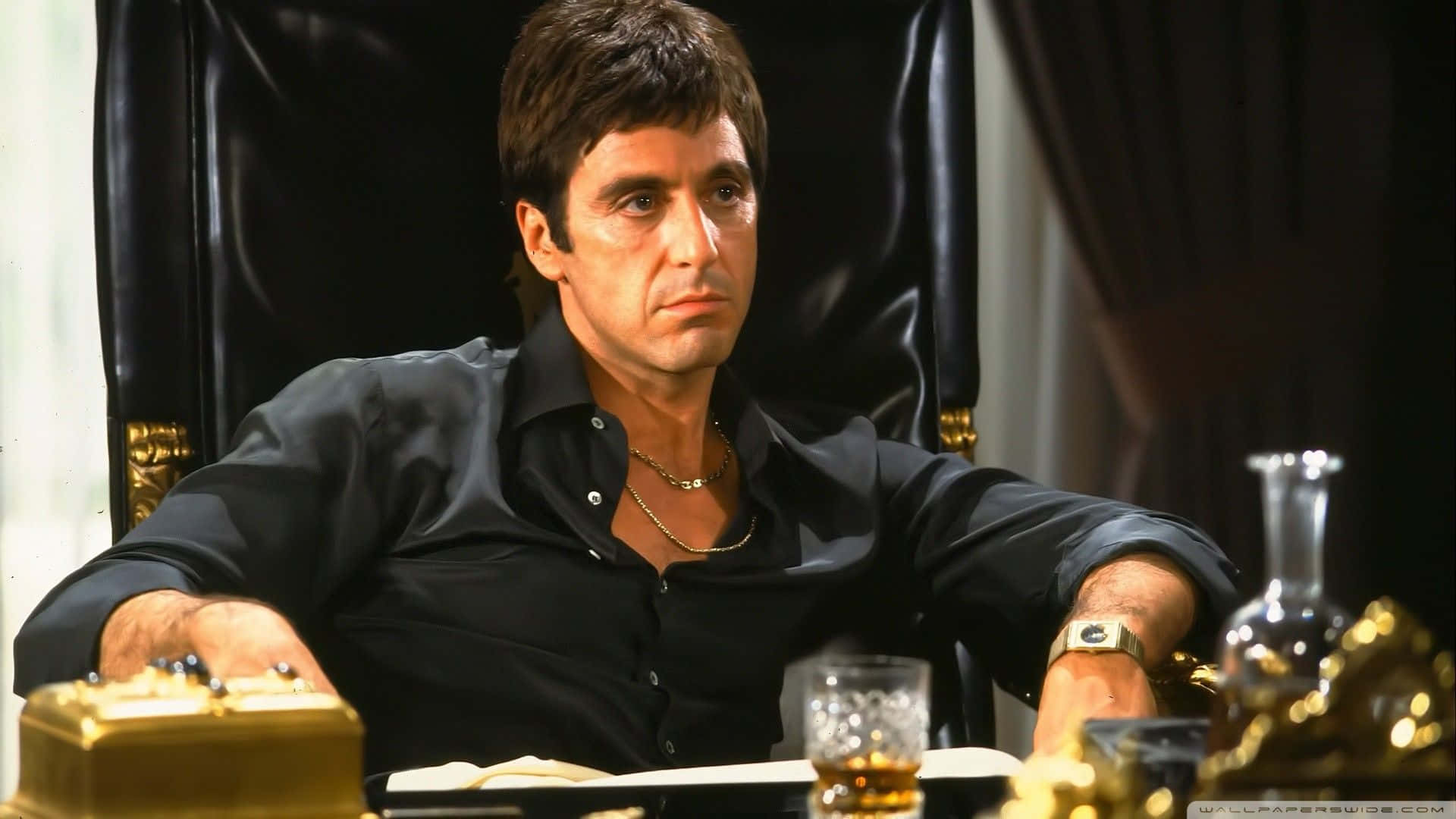Al Pacino 桌布 壁紙 — 一名身穿黑色襯衫的男子威嚴地坐在一張帶有金色裝飾的皮椅上，周圍環繞著威士忌和華麗的裝飾。