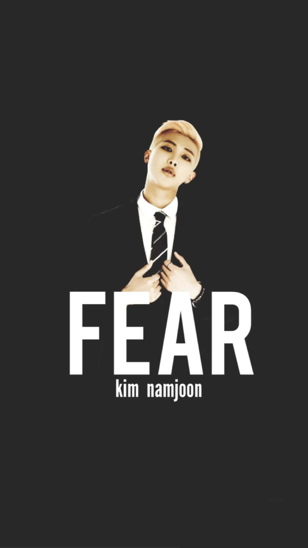 Bts Rap Monster 桌布 壁紙 — 一名身穿黑色西裝和條紋領帶的男子站在深色背景前，背景上有粗體白色文字「FEAR」。