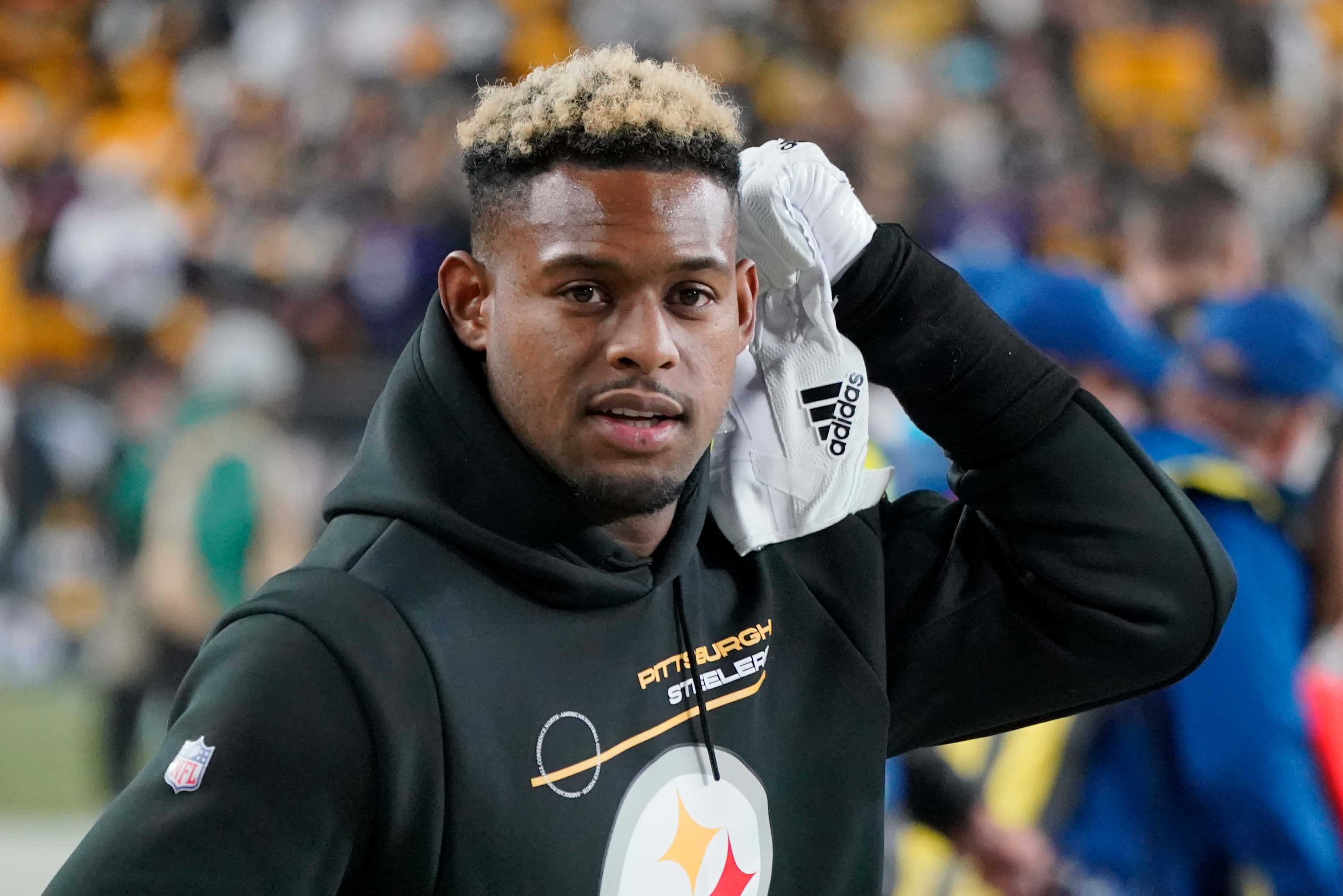Juju Smith Schuster 桌布 壁紙 — 一名身穿黑色連帽衫的匹茲堡鋼人隊美式足球員在體育場球場上將白色手套放在頭上。