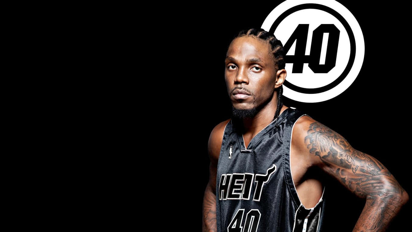 Udonis Haslem 桌布 壁紙 — 一名身穿黑色邁阿密熱火隊40號球衣的籃球運動員，自信地站在黑色背景前，身後有一個巨大的白色40號標誌。
