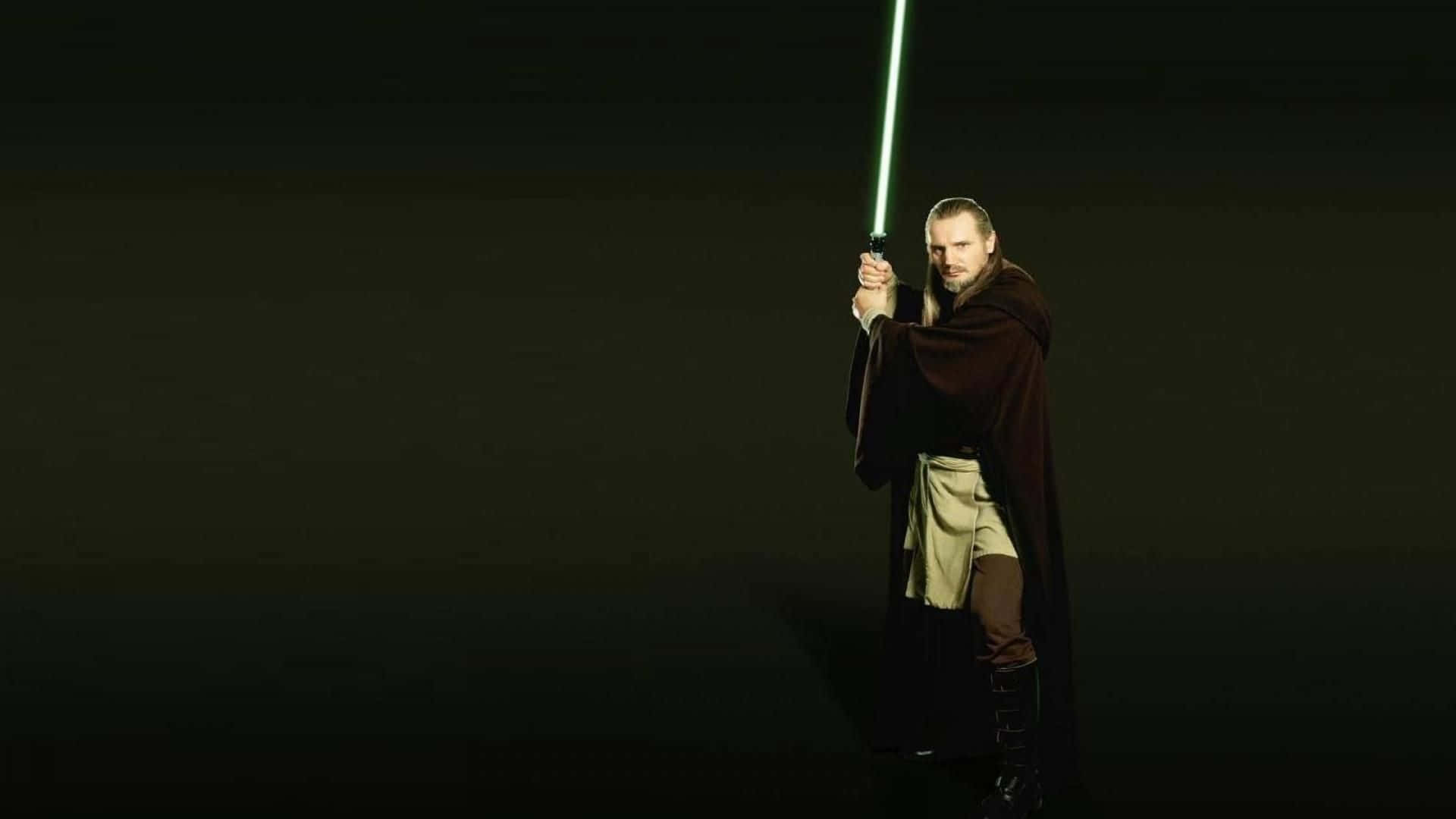 Qui-gon Jinn 桌布 壁紙 — 一名身穿黑色長袍的絕地武士在黑色背景下手持發光的綠色光劍。