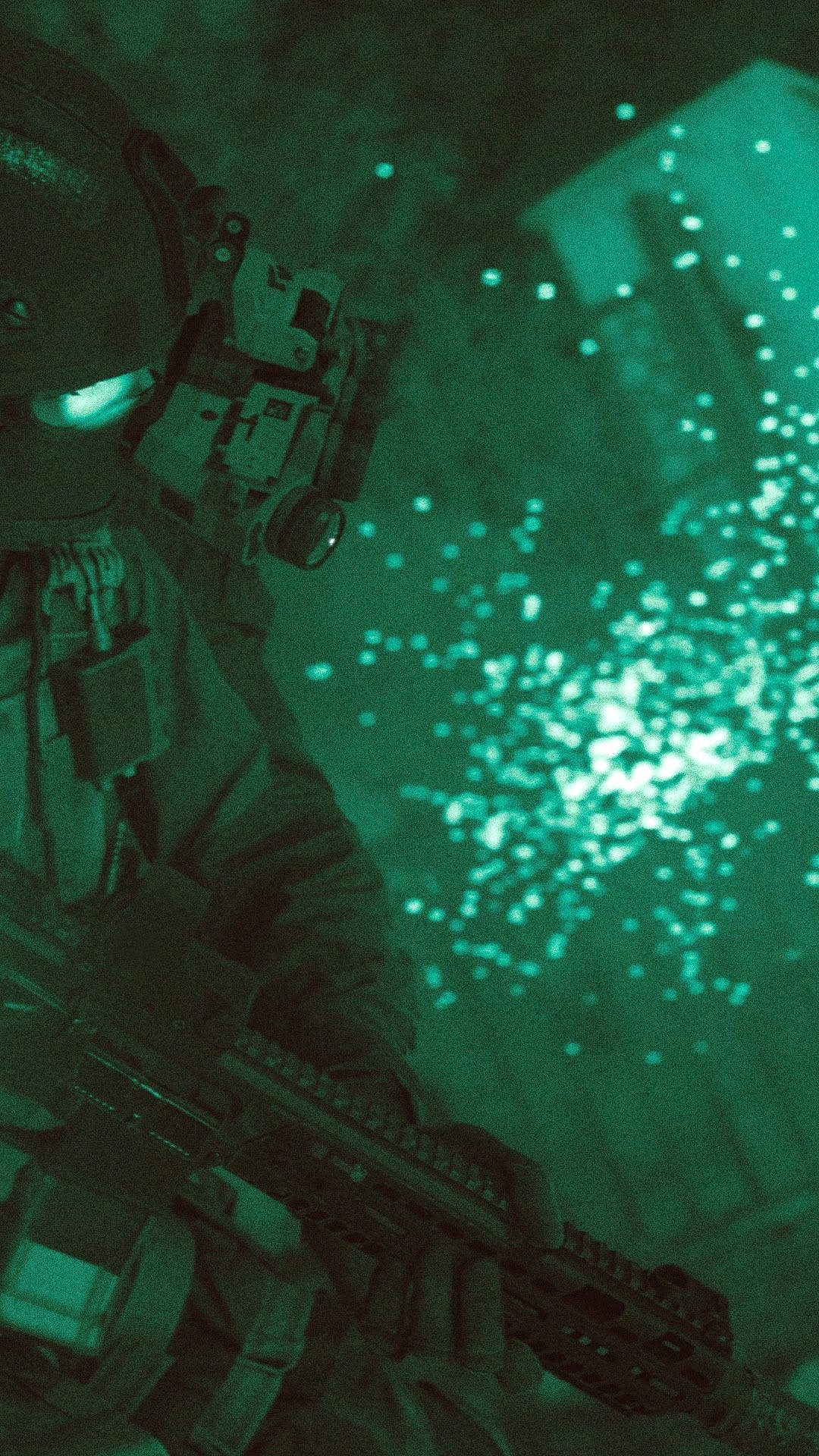 Call Of Duty Modern Warfare iPhone 桌布 壁紙 — 一名配備夜視裝備的士兵在昏暗的戰場上，於發光的綠色粒子中手持步槍。