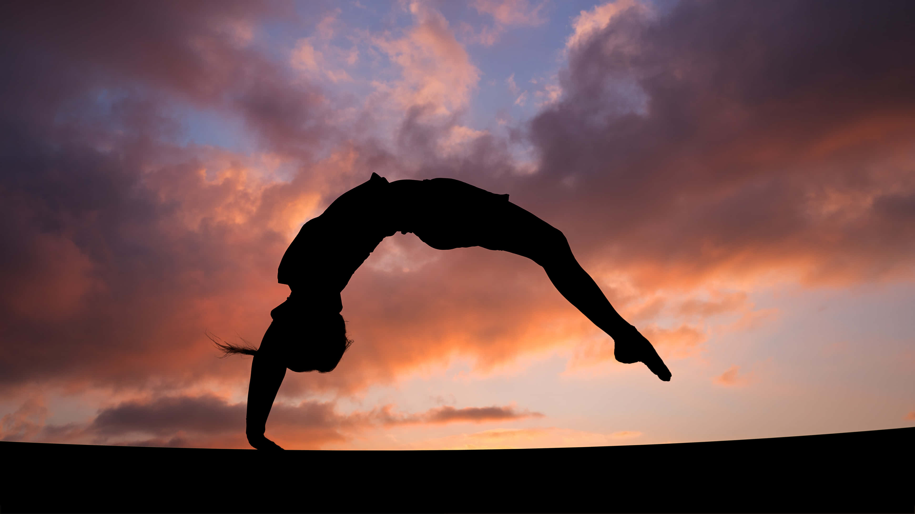Gymnastics 桌布 壁紙 — 一名體操運動員在火橙色和深紫色繪成的戲劇性日落天空下完美地表演後空翻。