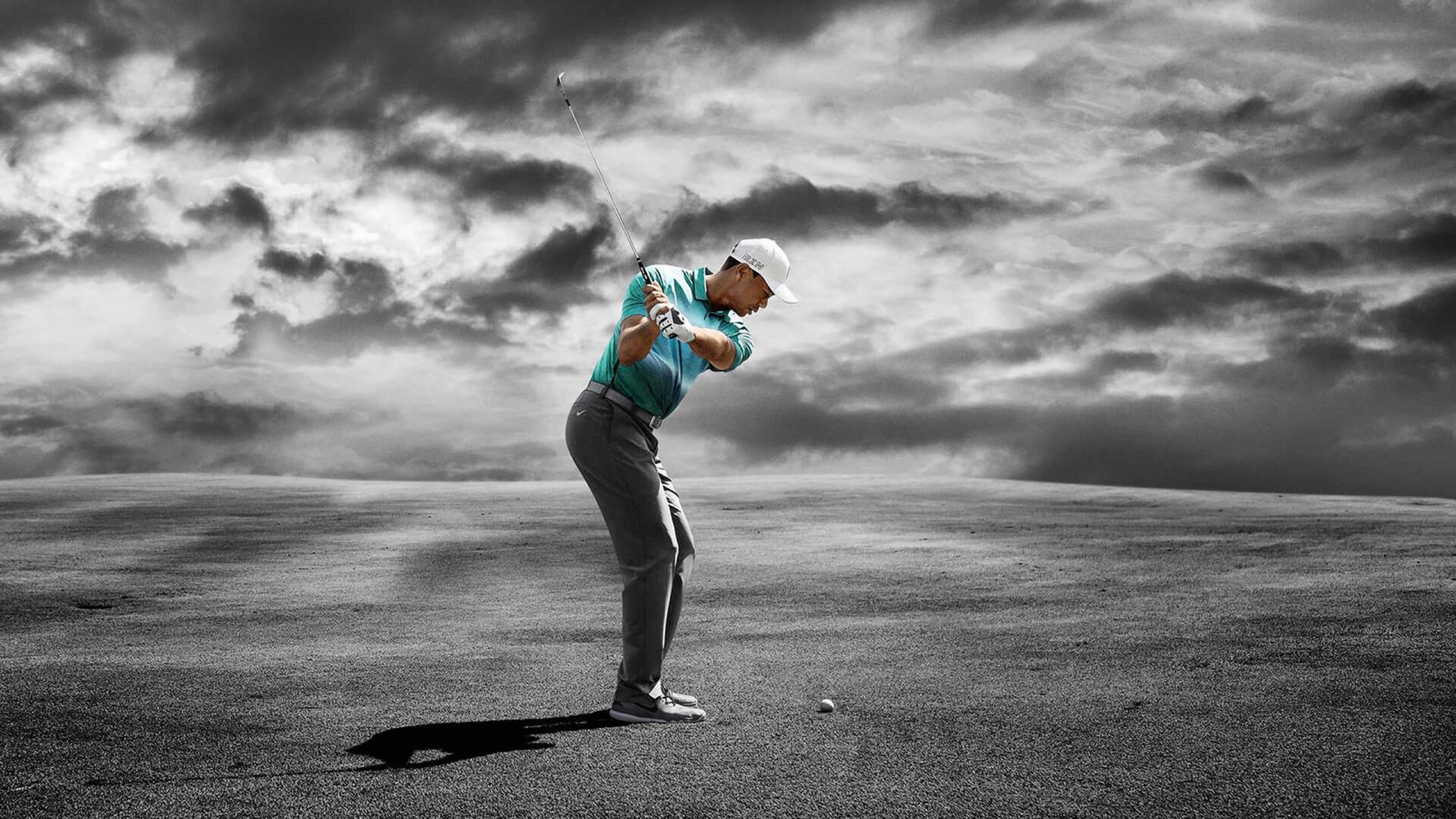 Tiger Woods Nike Velocity 壁紙 — 一名高爾夫球手在揮桿中途，背景是戲劇性的單色天空，襯衫上有選擇性色彩。