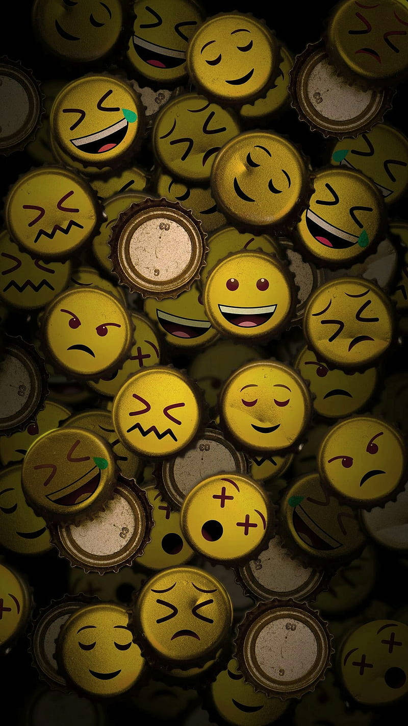 emoji 桌布 壁紙 — 一堆密集的黃色瓶蓋，每個瓶蓋在昏暗燈光下印有不同的表情符號面孔。