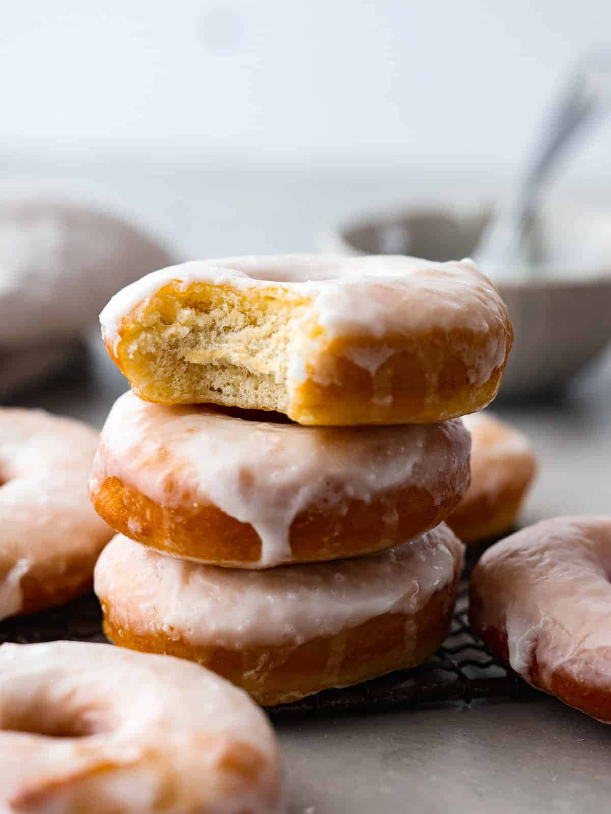Glazed Donut 桌布 壁紙 — 一堆糖霜冬甩，其中一個被咬了一口，露出軟綿綿的內部，放在冷卻架上。
