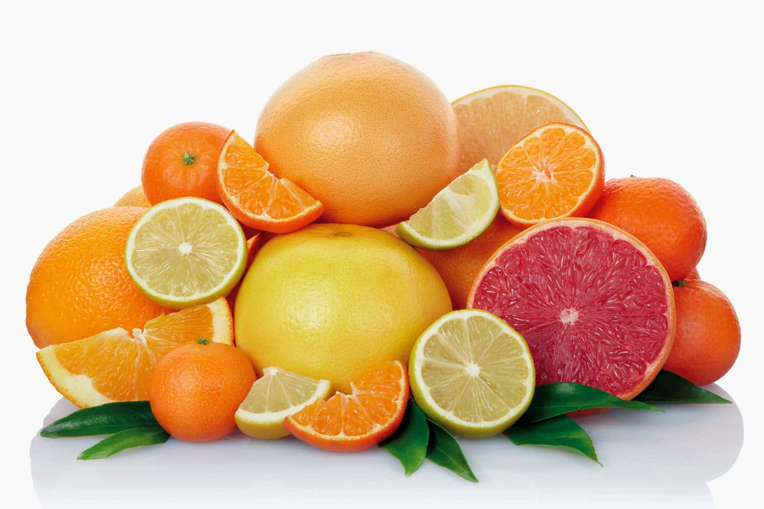 Winter Fruits 桌布 壁紙 — 一堆色彩鮮豔的各種柑橘類水果，包括橙、西柚和青檸，帶有綠葉，放在白色反光表面上。
