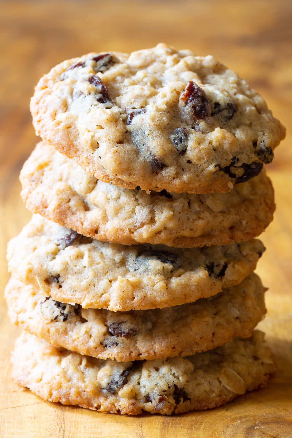 Cookie 桌布 壁紙 — 一堆高高的溫暖金黃色燕麥提子曲奇，可見燕麥片和飽滿的提子乾，誘人地放在木質表面上。