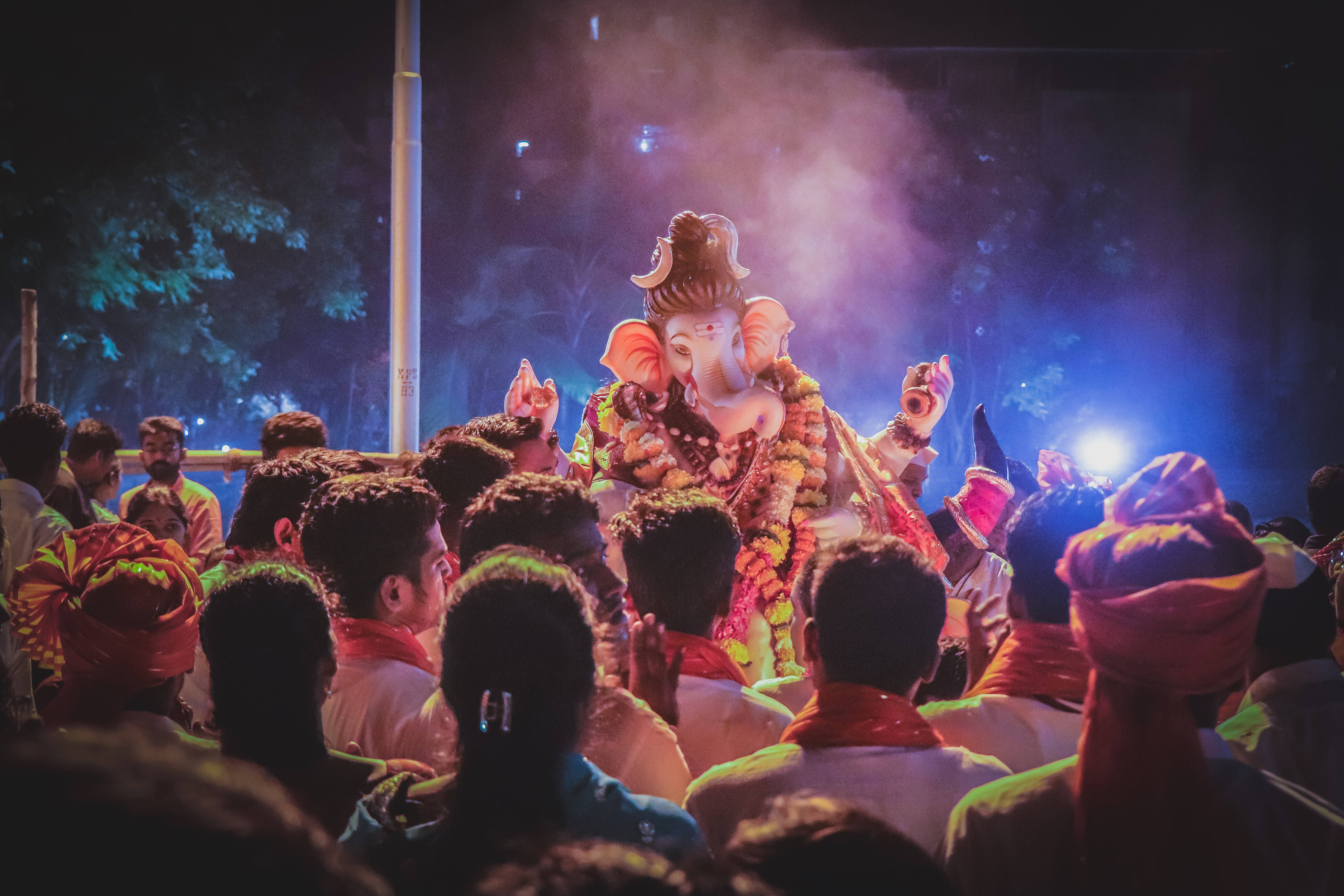 Ganesh Chaturthi 桌布 壁紙 — 一場充滿活力的夜間遊行，以一個大型發光的象神雕像為特色，周圍環繞著戴著彩色頭巾的信徒。