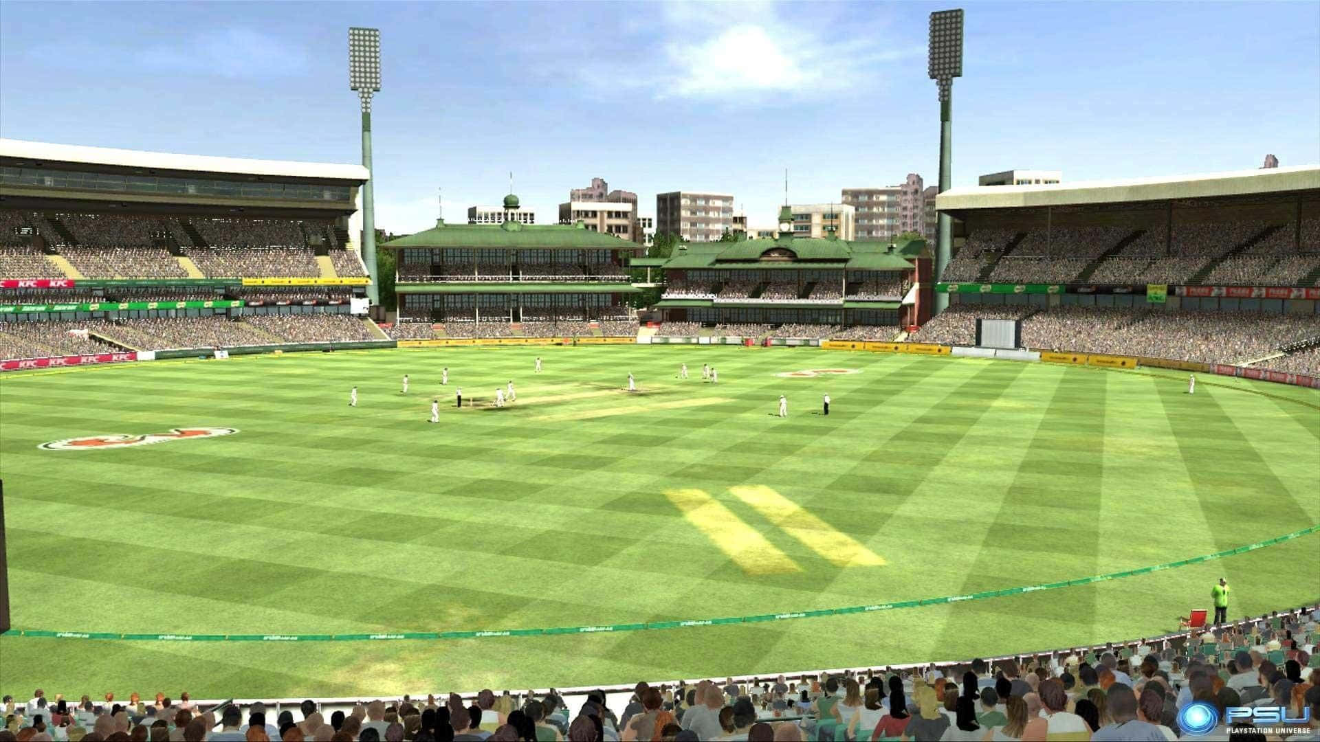 Cricket Ground 桌布 壁紙 — 一場充滿活力的板球比賽在明亮的日光下展開，球場座無虛席，綠草如茵，高聳的泛光燈矗立其中。