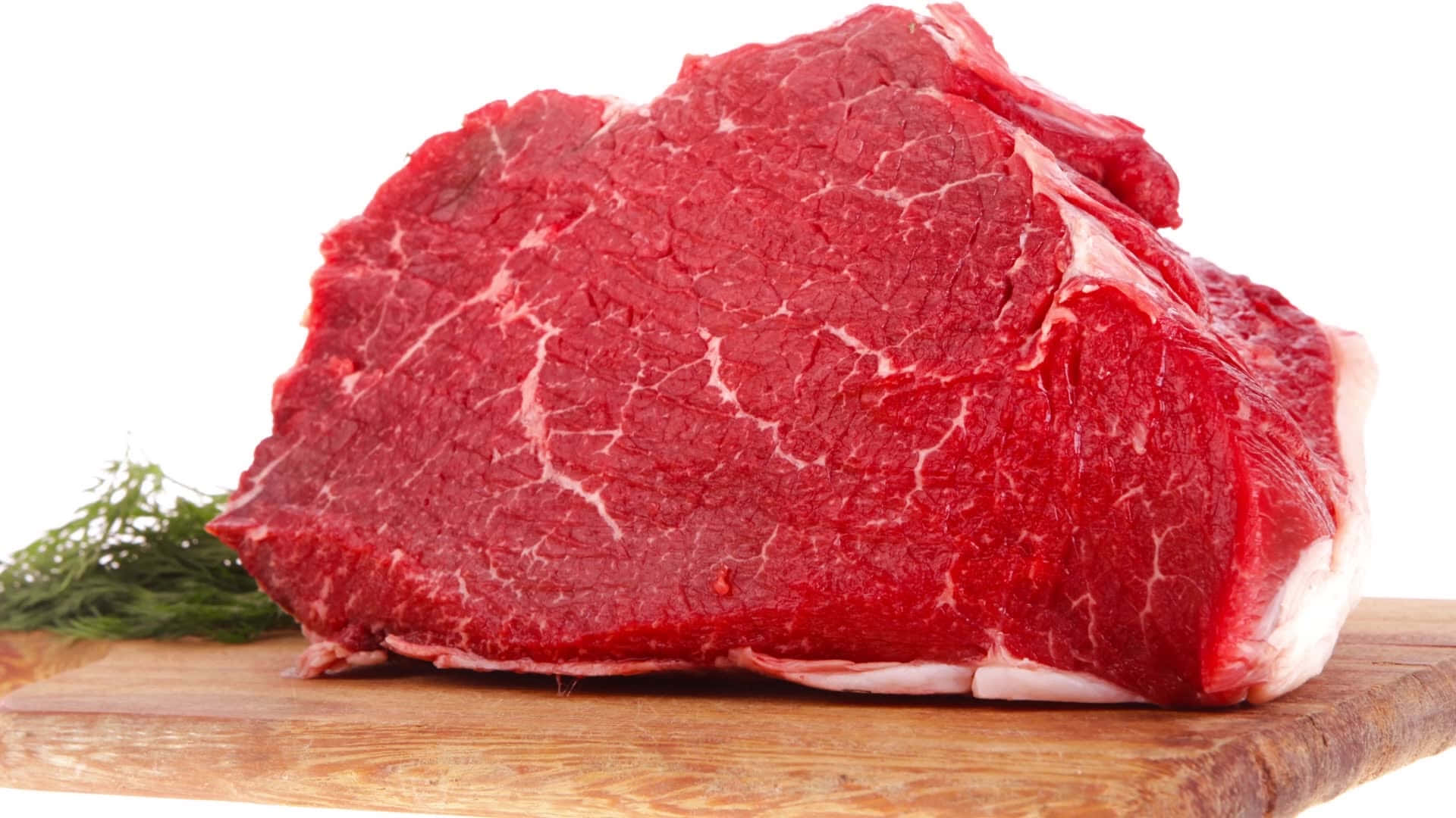 meat 桌布 壁紙 — 一塊多汁嘅生牛肉扒，帶有雪花紋理，放喺木砧板上，旁邊有新鮮刁草，背景係白色。