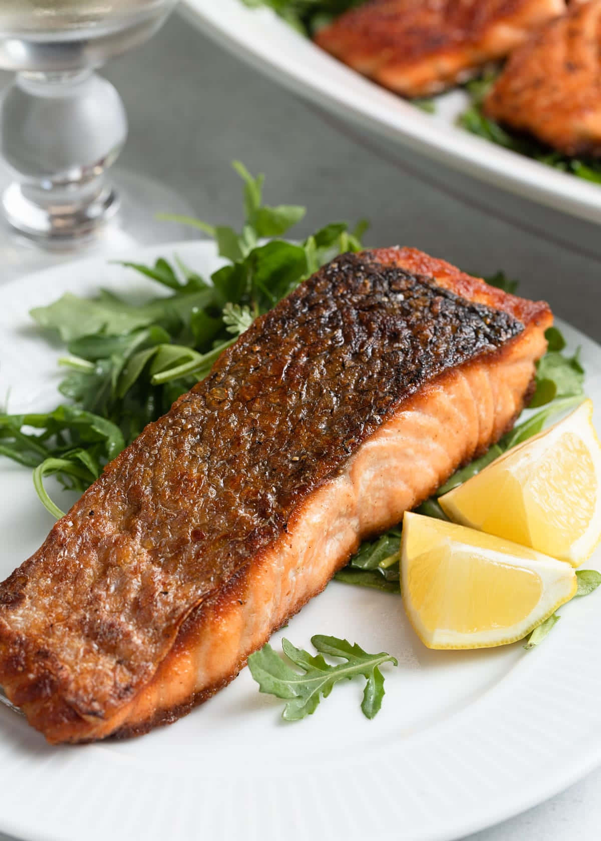 Salmon 桌布 壁紙 — 一塊完美煎封的三文魚柳放在火箭菜上，配以檸檬角，置於白色碟中。