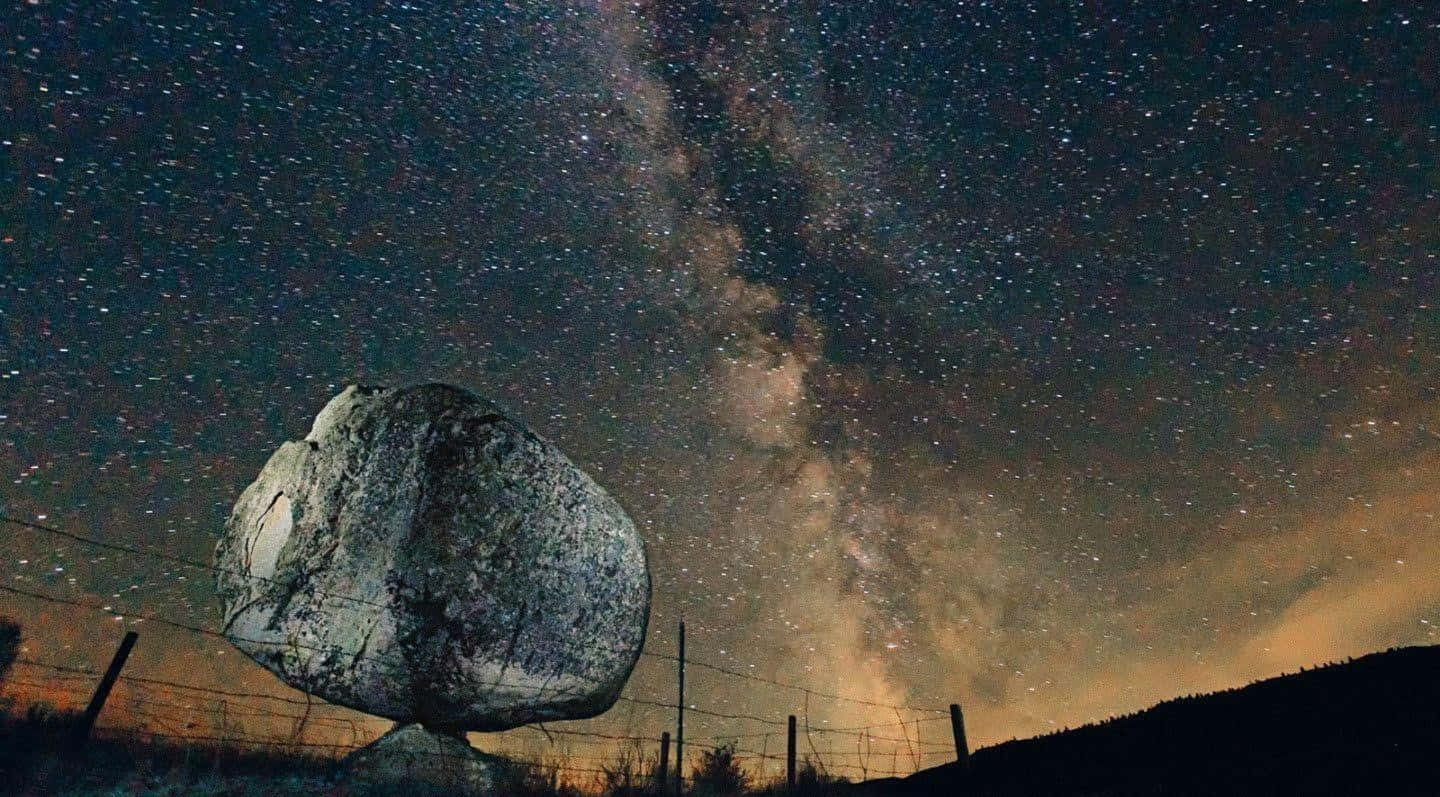 銀河系 桌布 壁紙 — 一塊巨大的岩石坐落於繁星點點的夜空下，銀河在頭頂閃耀。
