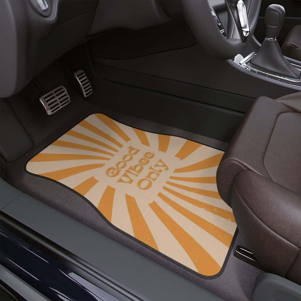 Minimalist Car 桌布 壁紙 — 一塊帶有太陽光線圖案及「good vibes only」文字的汽車地墊，放置於現代汽車內飾的駕駛者腳坑中。