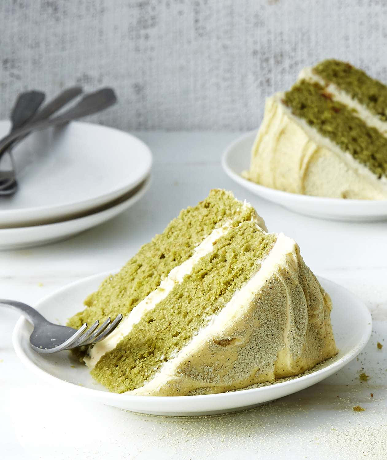 Buttercream 桌布 壁紙 — 一塊濕潤的綠茶蛋糕，配上 creamy 白色糖霜，放在白色碟上，旁邊有一把叉。