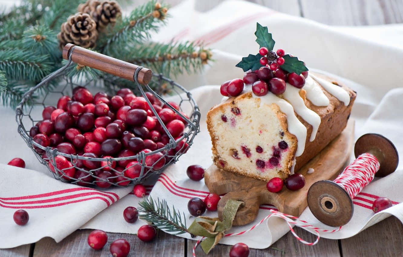 Winter Desserts 桌布 壁紙 — 一塊節日風味的蔓越莓麵包蛋糕，淋上白色糖霜，旁邊是一個裝滿新鮮蔓越莓和松果的鐵絲籃，放在質樸的木桌上。