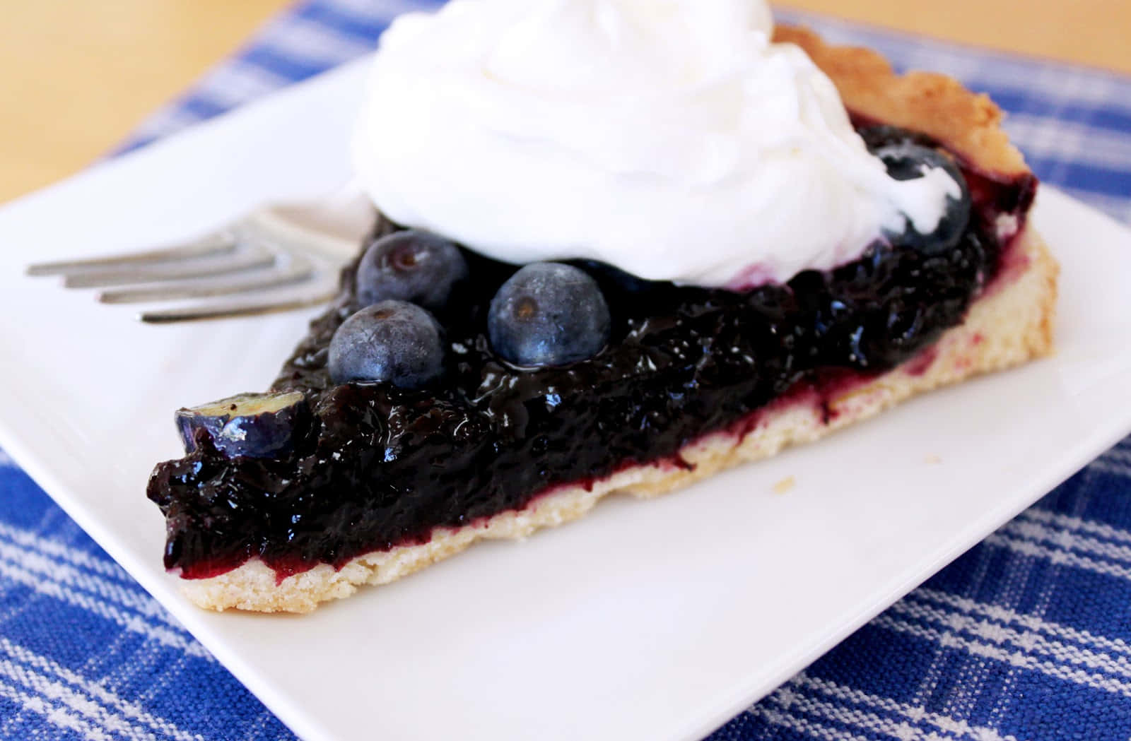 Blueberries Tart 桌布 壁紙 — 一塊藍莓批加上忌廉，放在白色碟上，碟下是藍色格仔布。