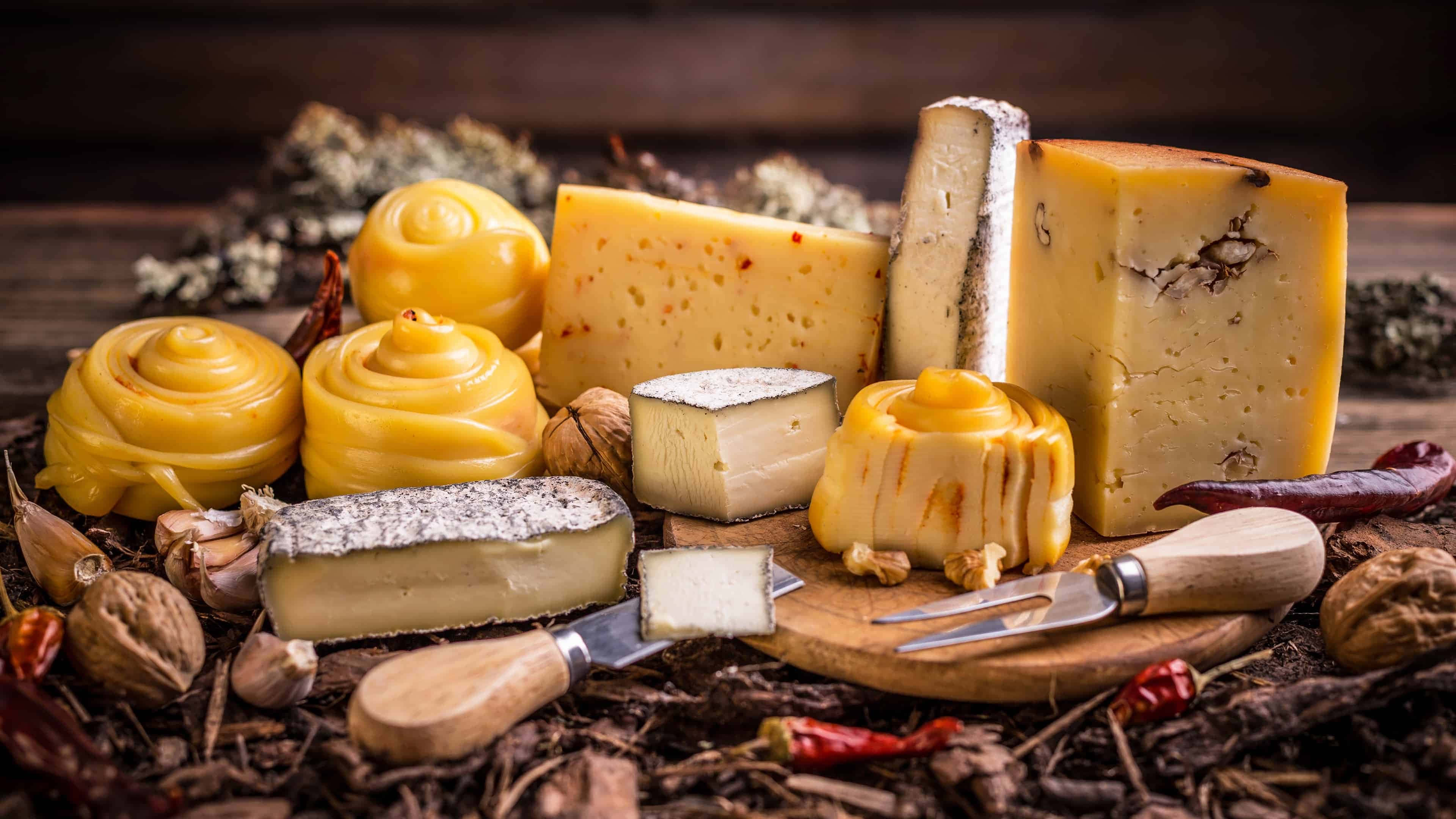 Cheese 桌布 壁紙 — 一塊質樸的木板上展示了藝術擺盤的各式芝士，搭配堅果和乾辣椒。