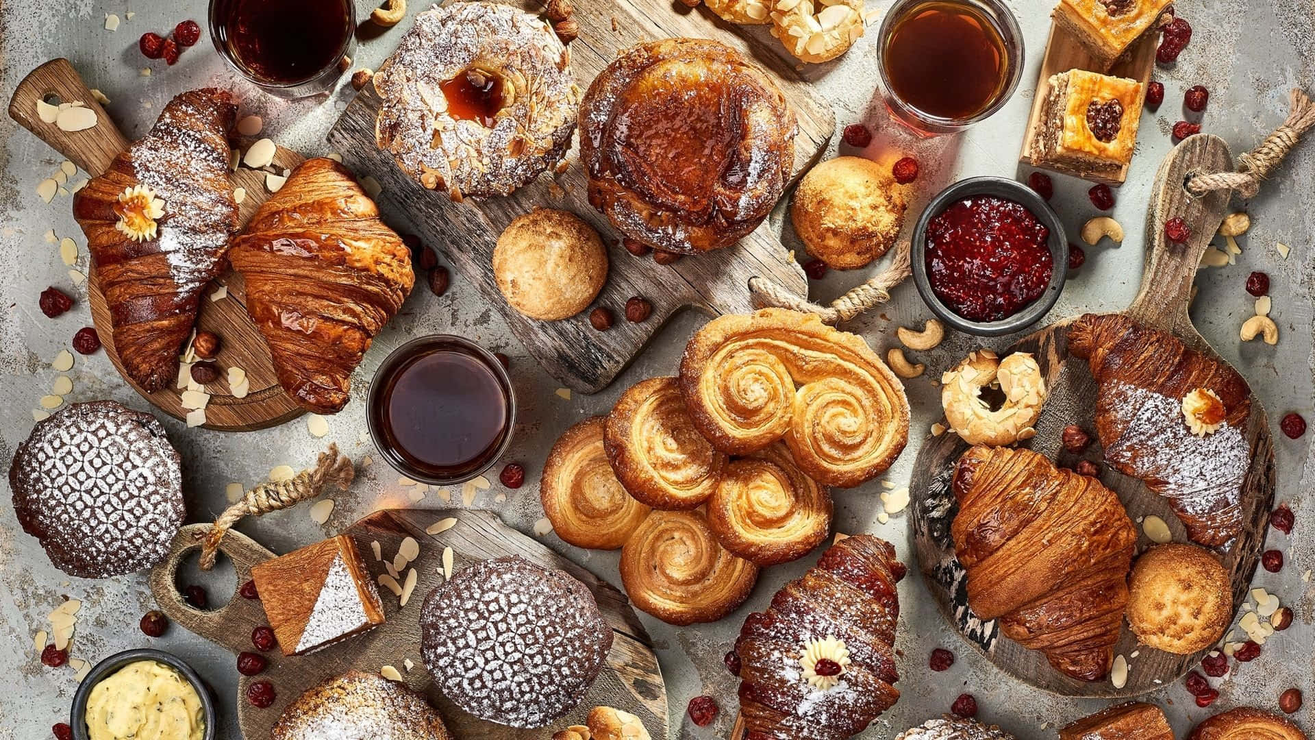 Pastry 桌布 壁紙 — 一塊質樸的木板上擺放著各種金黃色的糕點、牛角包、丹麥酥和果醬，營造出舒適的早餐氛圍。
