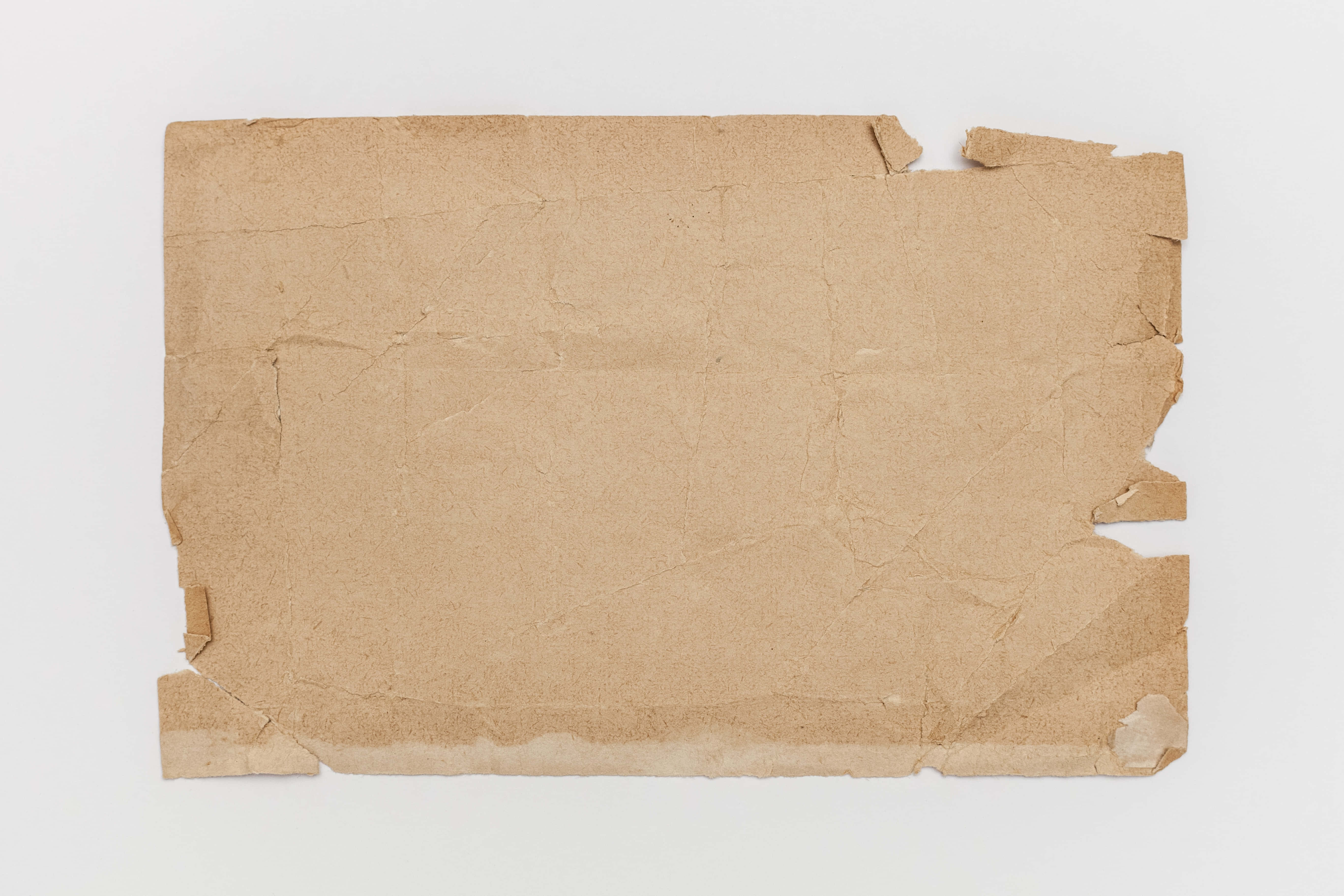 Brown Paper 桌布 壁紙 — 一塊邊緣粗糙的棕色牛皮紙碎片平放在純白色背景上。