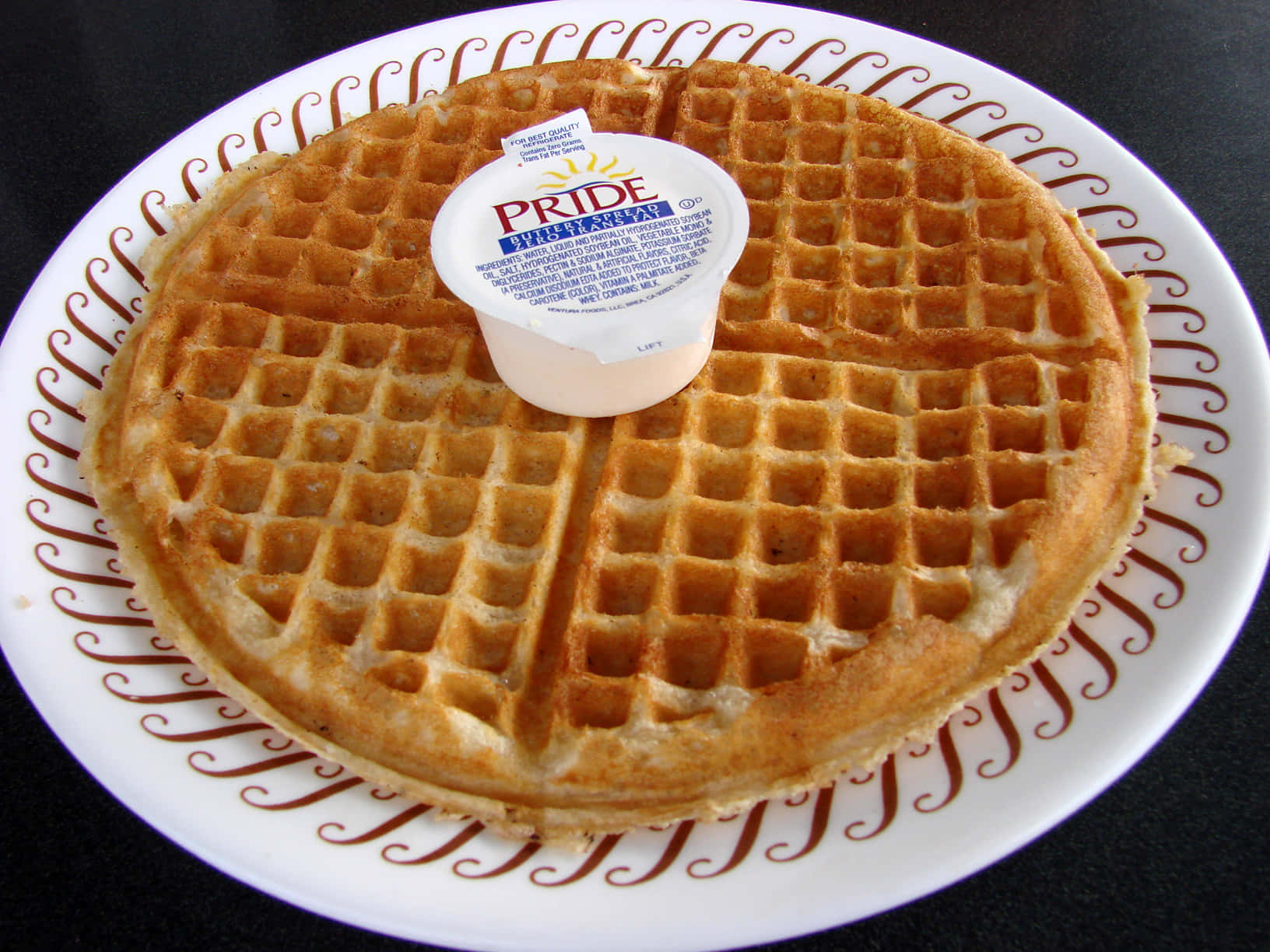 Waffle 桌布 壁紙 — 一塊金黃色的窩夫放在帶有棕色渦紋的白色碟上，上面放著一小盒牛油。