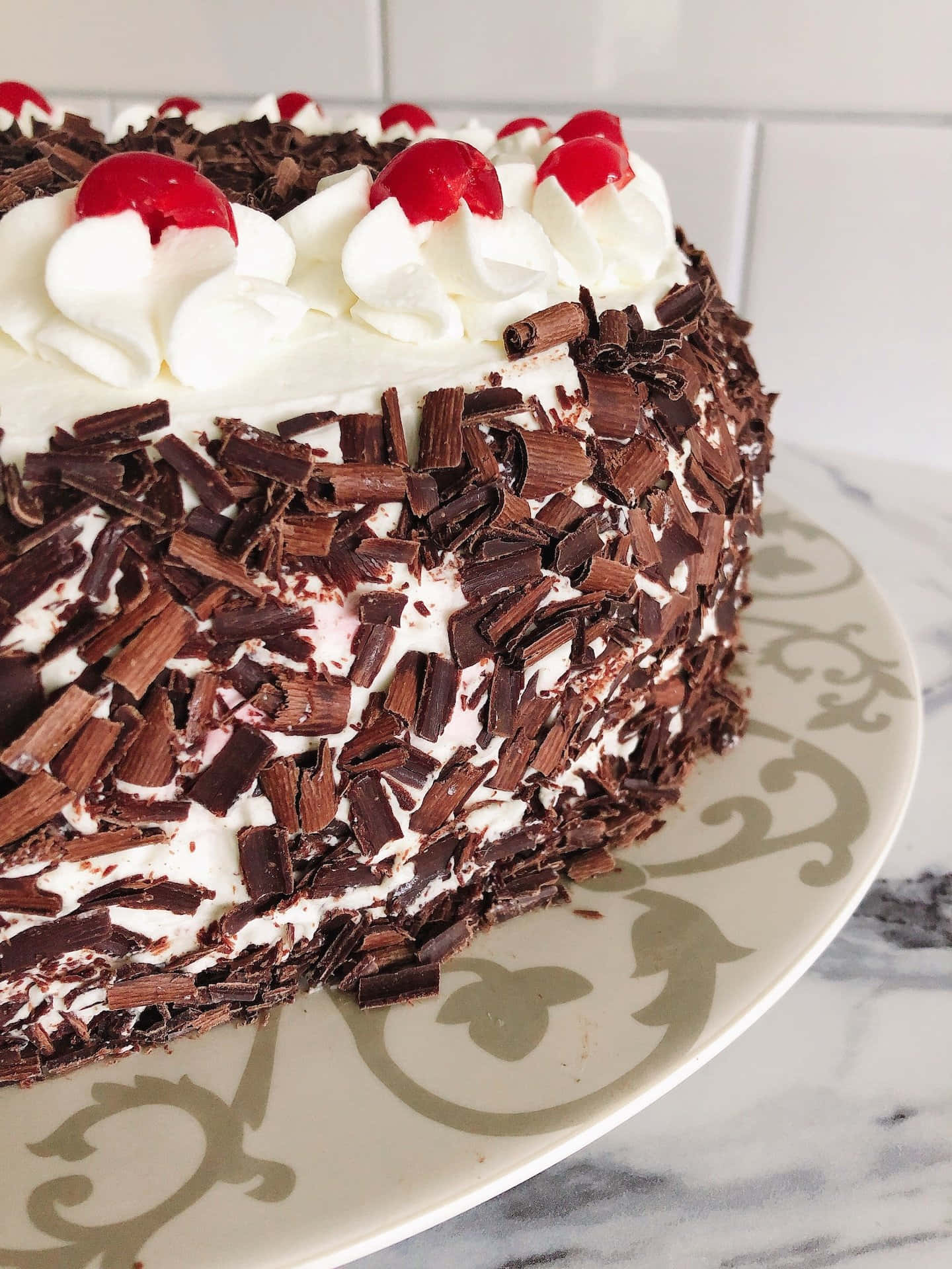Black Forest Cake 桌布 壁紙 — 一塊頹廢的黑森林蛋糕，上面有鮮奶油和櫻桃，放在華麗的盤子上，背景是大理石。