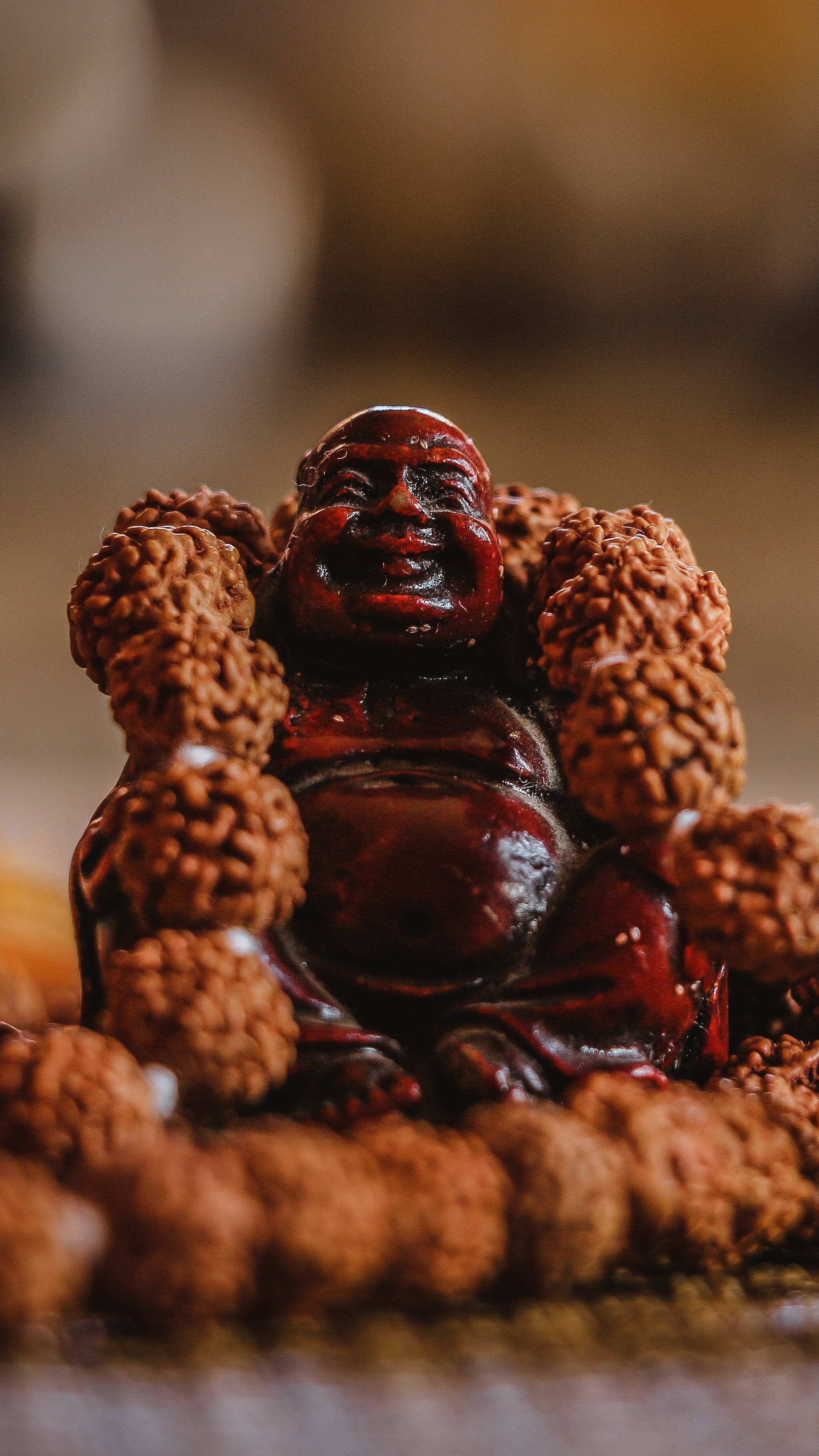 Buddha 桌布 壁紙 — 一尊光滑的木製笑佛雕像，周圍環繞著質感豐富的念珠，色調溫暖樸實。