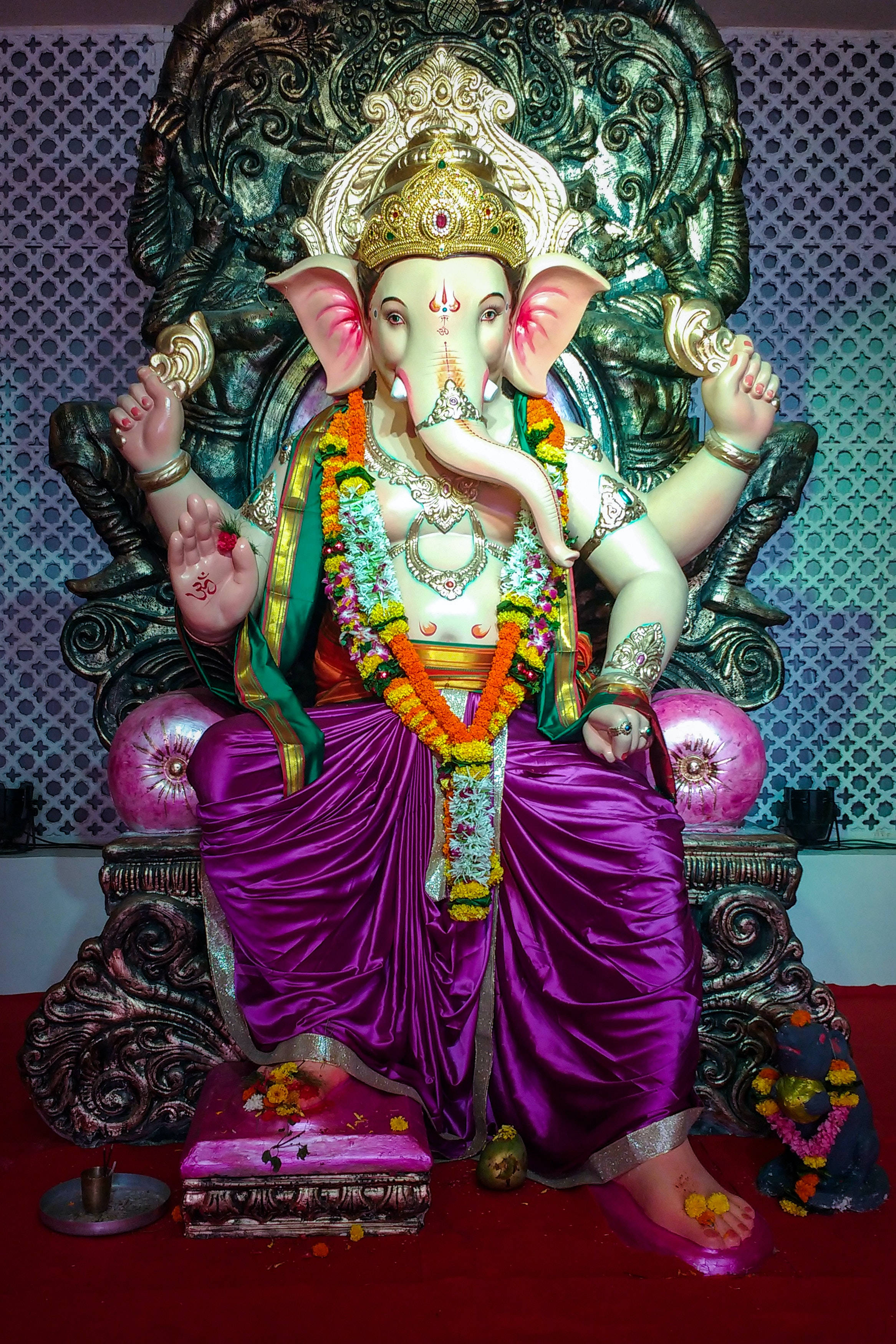 Ganesh 桌布 壁紙 — 一尊宏偉的象神坐像，裝飾著鮮豔的紫色絲綢和花環，襯托著華麗的深色寶座。