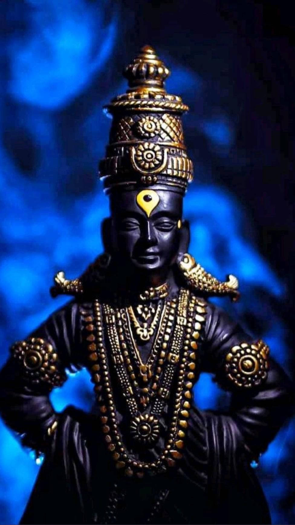 Lord Shiva 桌布 壁紙 — 一尊深色皮膚的神像，飾以精緻的金飾，站在發光的藍色煙霧背景前。